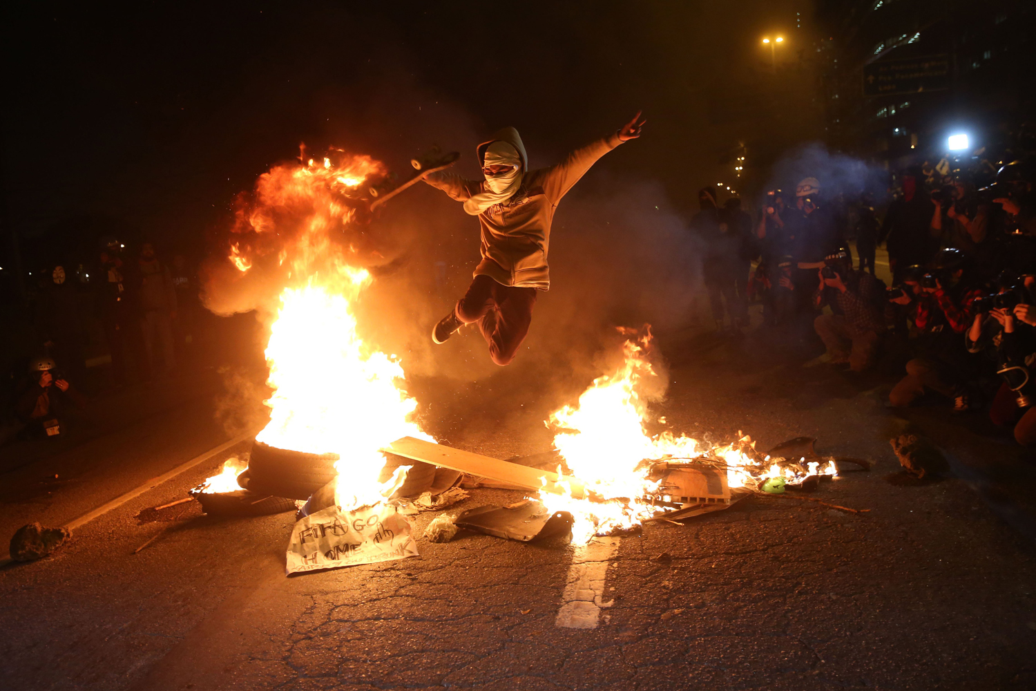 A protester jumps over a fire barricade during a protest against 2014 FIFA World Cup in Sao Paulo, on June 19, 2014.