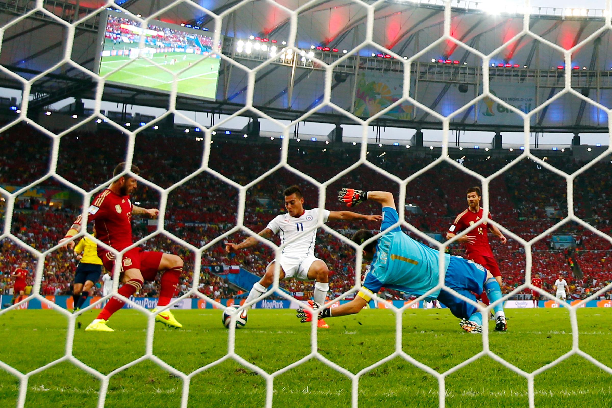 Eduardo Vargas of Chile shoots and scores his team's first goal past Sergio Ramos and goalkeeper Iker Casillas of Spain during the 2014 FIFA World Cup Brazil Group B match between Spain and Chile at Maracana on June 18, 2014 in Rio de Janeiro.