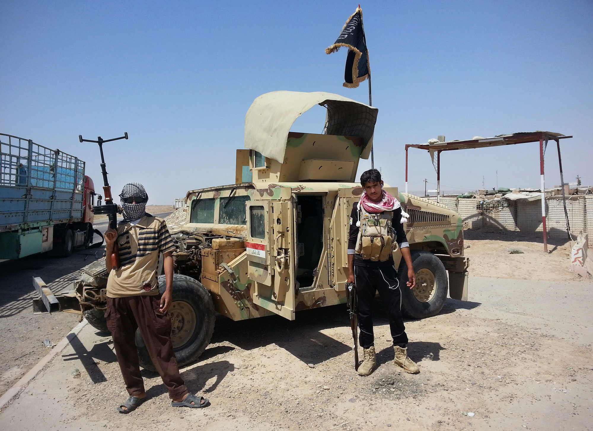 Al-Qaeda inspired militants stand with captured Iraqi Army Humvee at a checkpoint belonging to Iraqi Army outside Beiji refinery some 155 miles north of Baghdad, June 19, 2014. (AP)