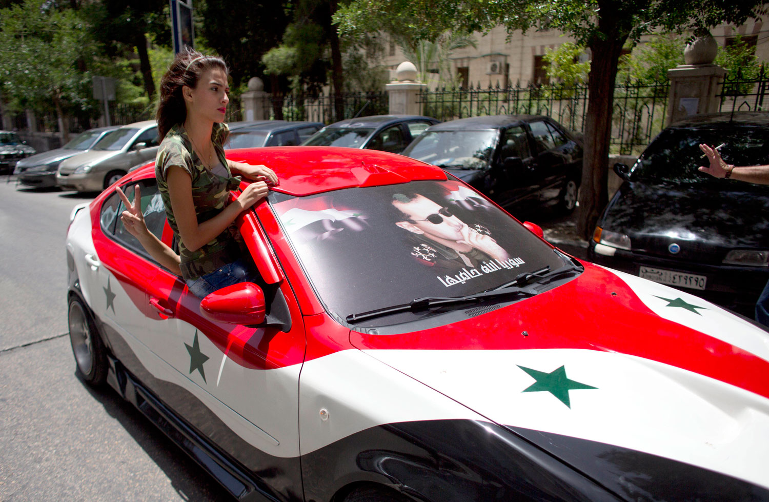 A Syrian woman rides in a car painted in the colors of the Syrian flag with President Bashar Assad's portrait in Damascus on June 3, 2014.