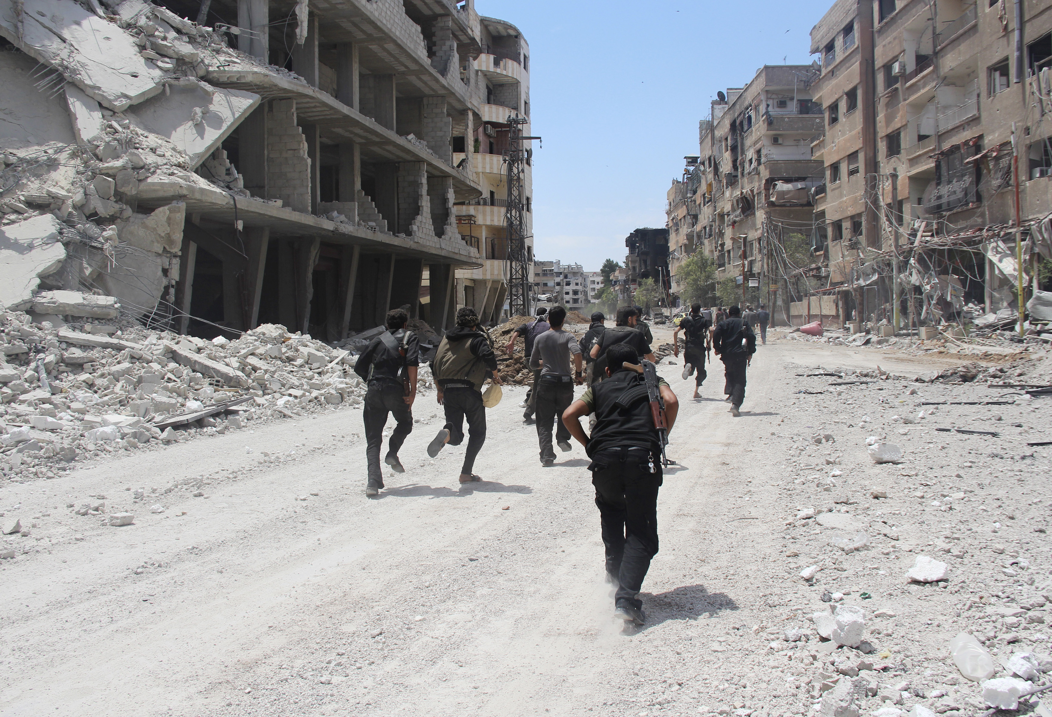 Rebel fighters carry their weapons as they run past damaged buildings to avoid snipers loyal to Syria's President Bashar al-Assad in the Mleha suburb of Damascus May 26, 2014. REUTERS/Badra Mamet (SYRIA - Tags: POLITICS CIVIL UNREST CONFLICT MILITARY) - RTR3QXRJ (Badra Mamet—Reuters)