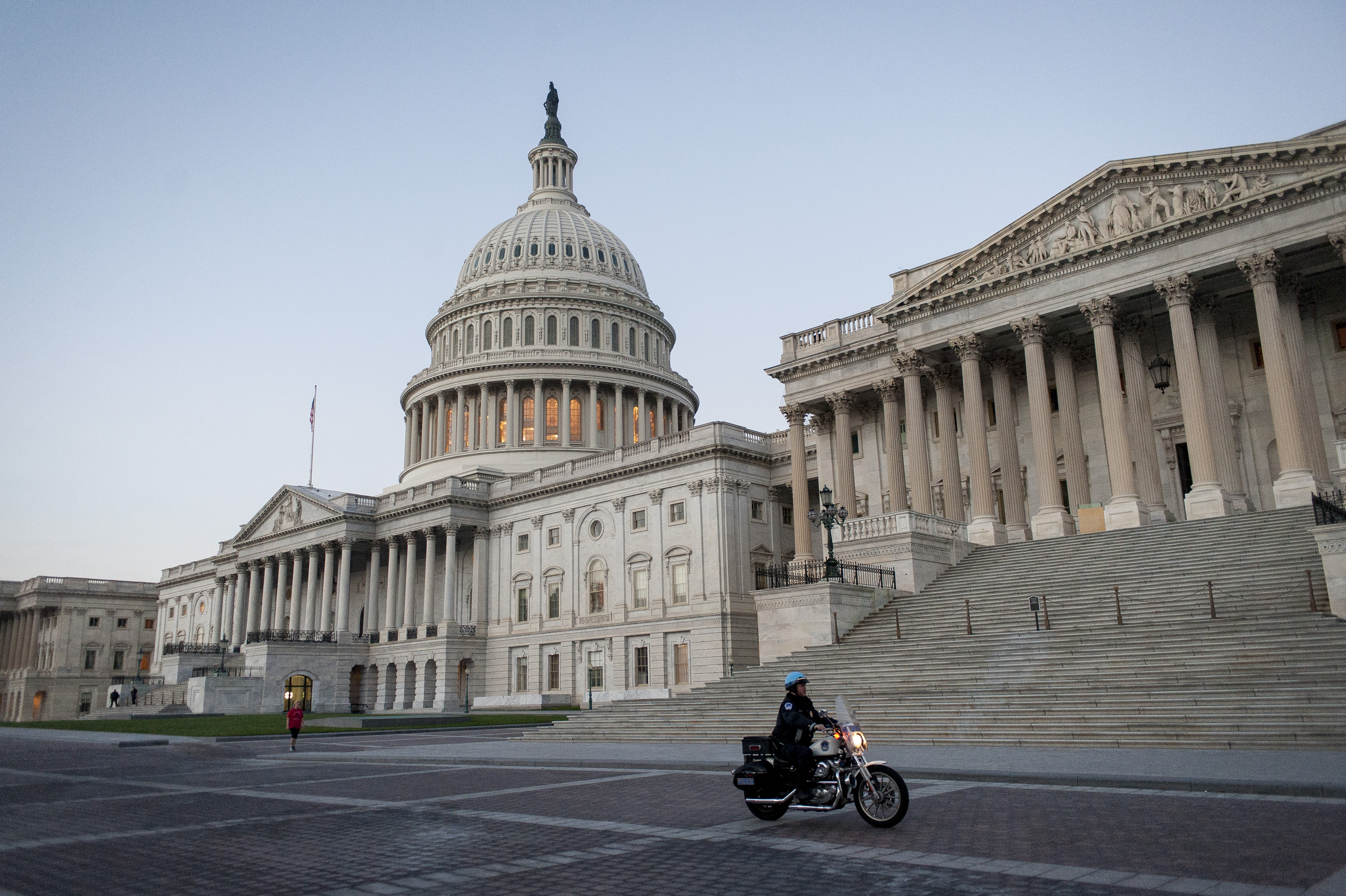 A police officer rides a motorcycle past the United States Capitol building at sunrise in Washington, D.C., U.S., on Tuesday, Oct. 15, 2013. (Pete Marovich—Bloomberg/Getty Images)