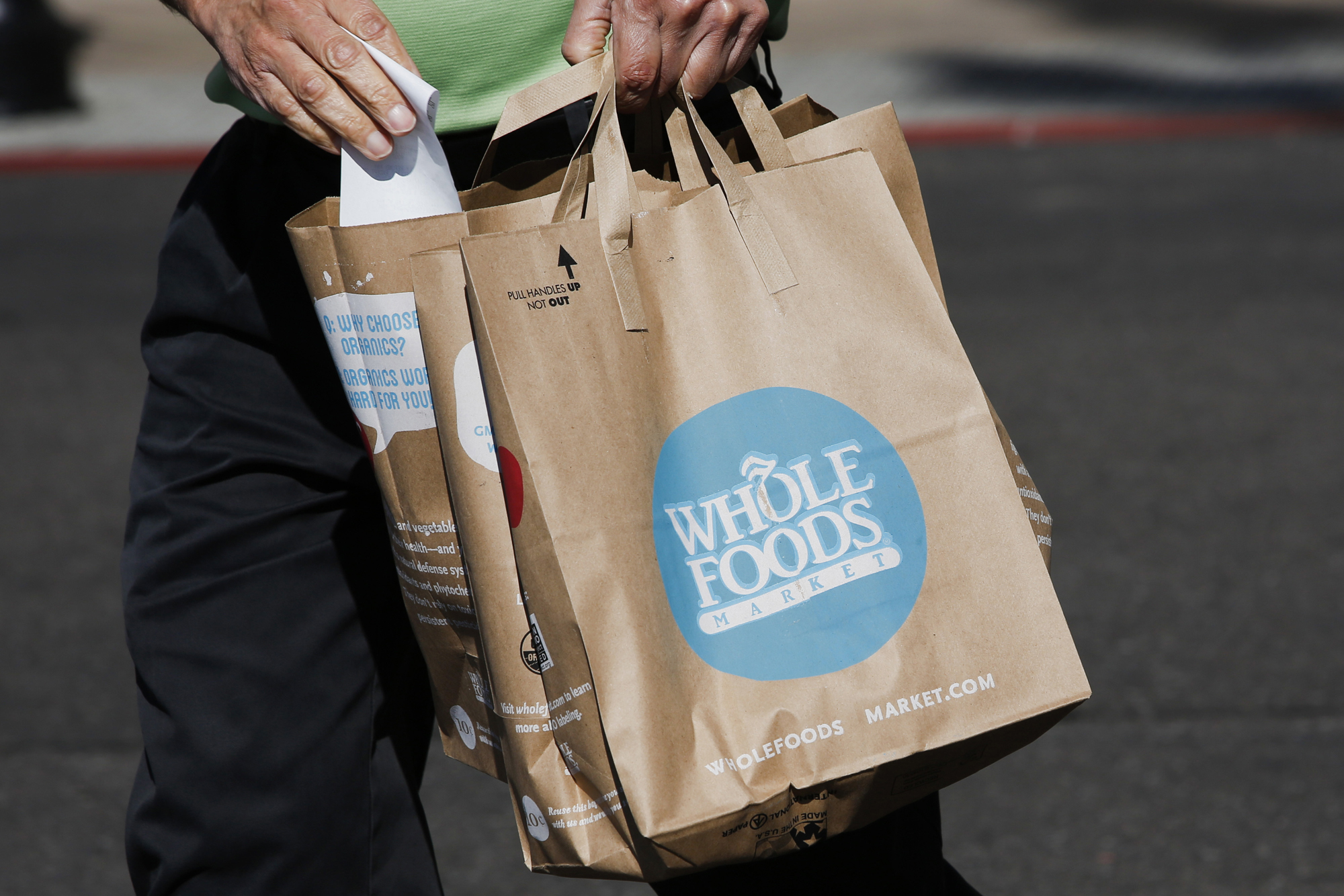 A customer carries shopping bags outside of a Whole Foods in El Segundo, Calif., Nov. 5, 2013.