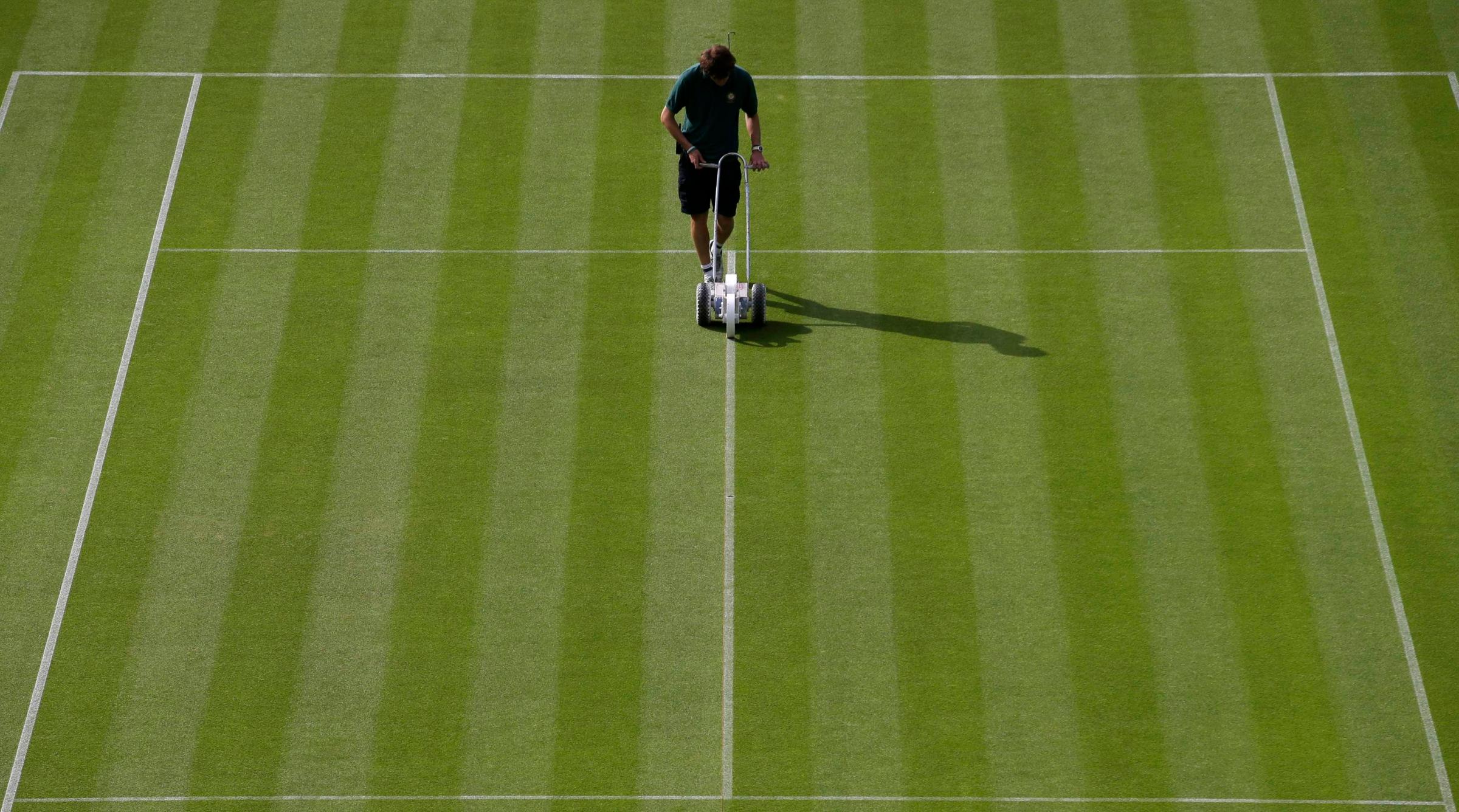 A worker paints lines on a court prior to the first day's play of the Wimbledon Tennis Championships, in London