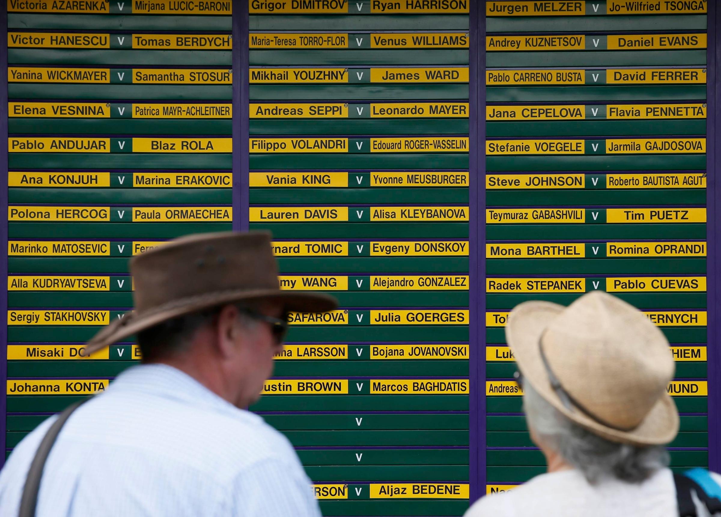 Fans look at a board showing the order of play at the Wimbledon Tennis Championships, in London