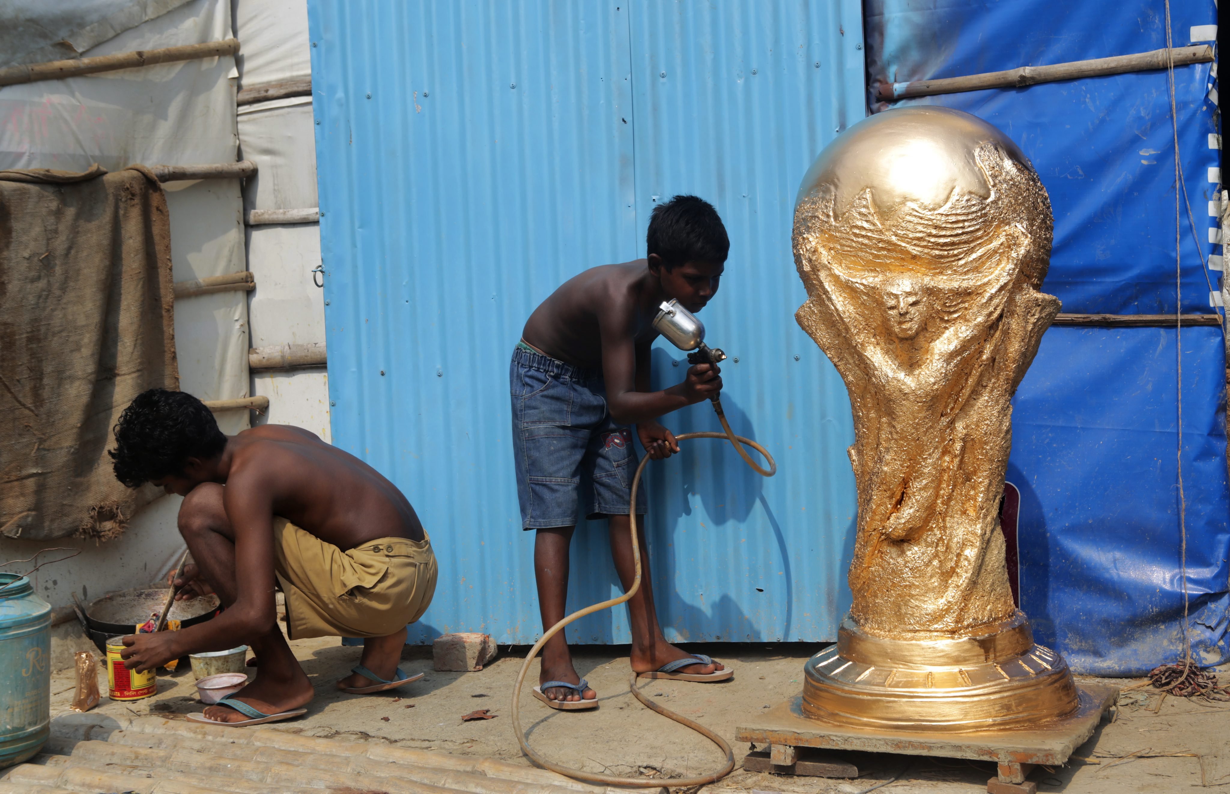 A young artist Kartik Das (C) applies color on a clay model of the FIFA World Cup trophy as a part of decoration for the forthcoming FIFA World Cup soccer tournament in Calcutta, India on June 9, 2014.