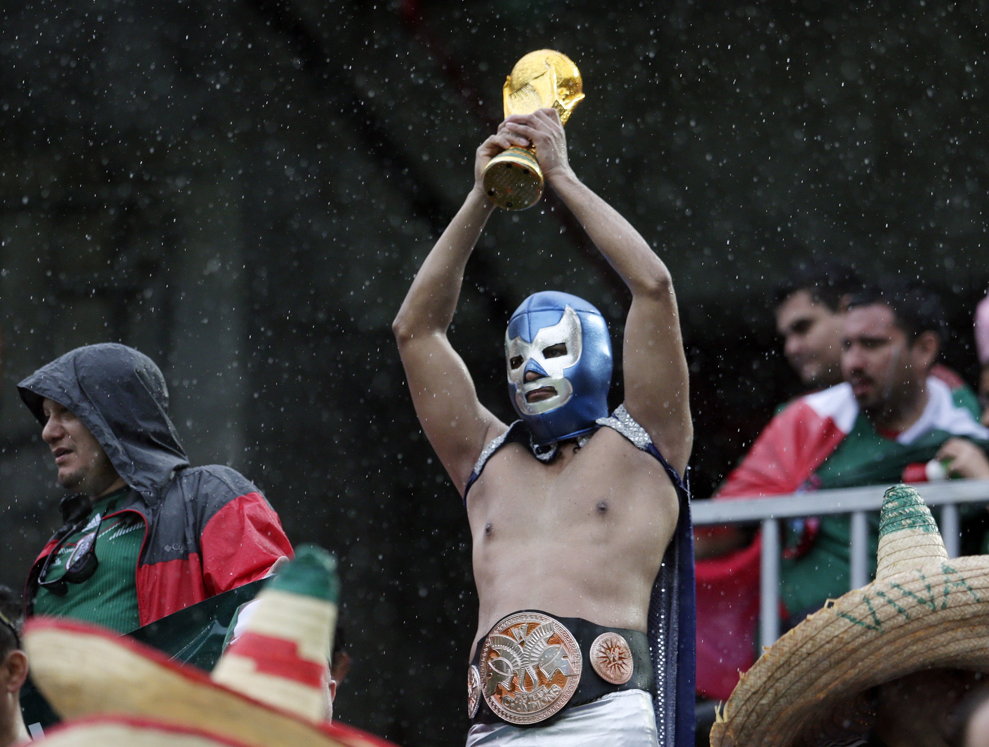 A Mexican fan holds up a replica of the World Cup trophy before the group A World Cup soccer match between Mexico and Cameroon in the Arena das Dunas in Natal, Brazil on Friday, June 13, 2014.