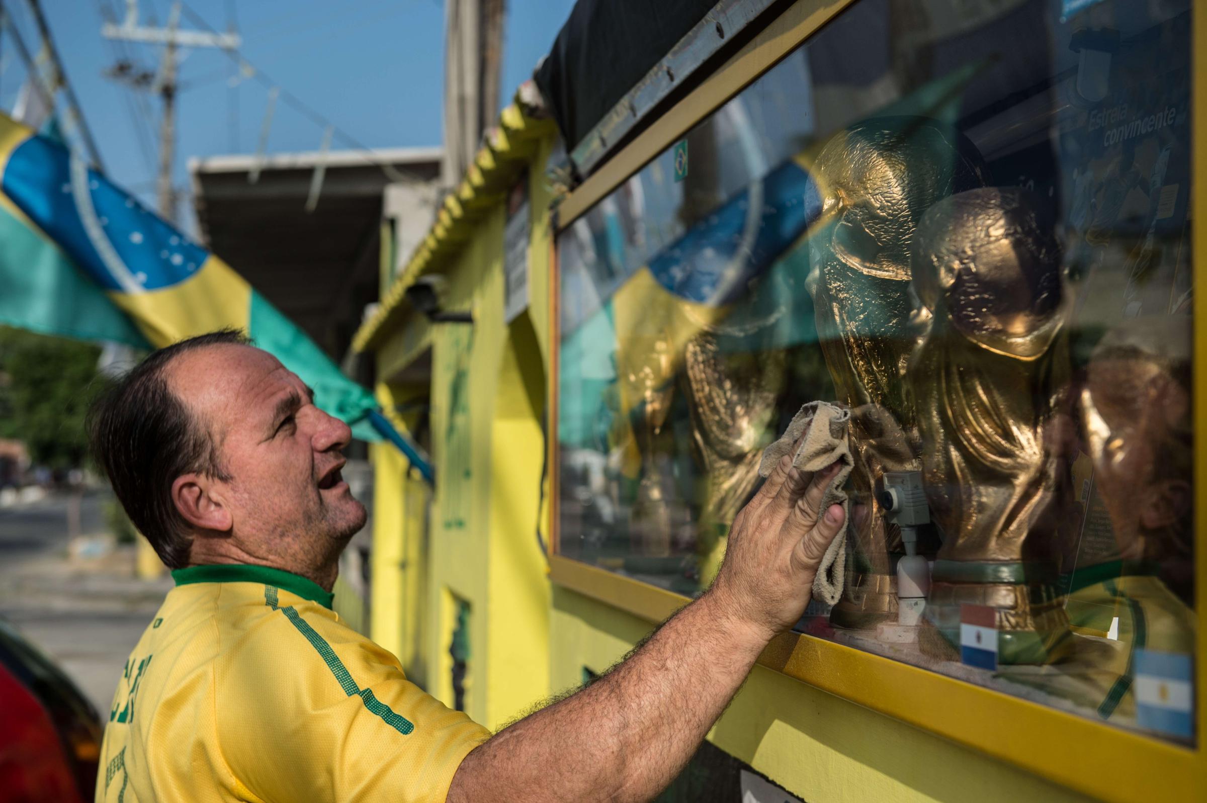 Jarbas Menighini, 46-year-old cleans the show-case set of trophies in front of his home on the day he is to see the first of four matches of the FIFA World Cup at Maracana stadium in Rio de Janeiro, Brazil, on June 18, 2014.