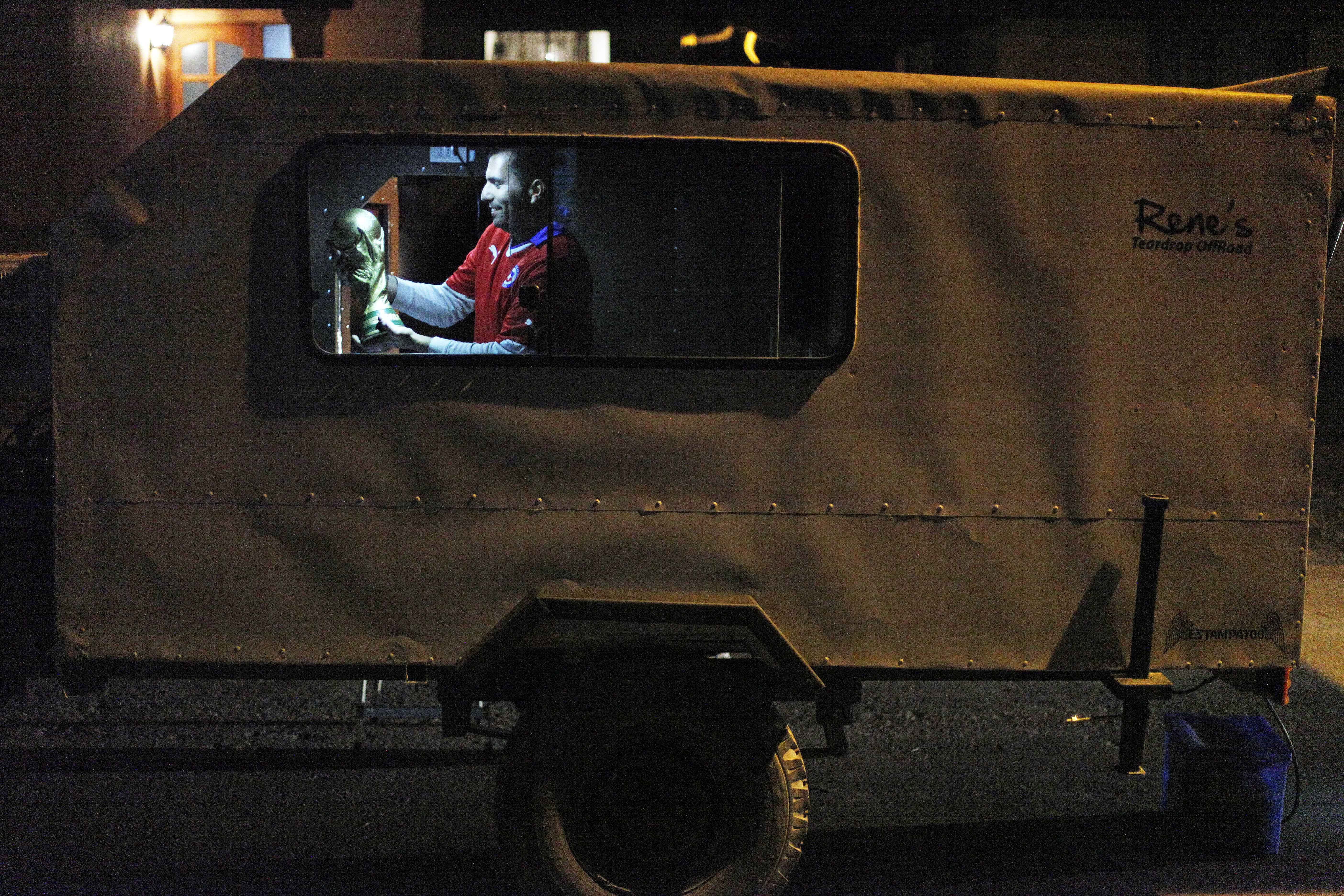 Chile soccer fan Cristian Uribarri holds up his replica of the World Cup trophy as he decides if he should take it and where to put it in his trailer, which he built from scratch, as he packs it for the next day's journey with four friends to Brazil from Santiago, Chile on jUne 5, 2014.
