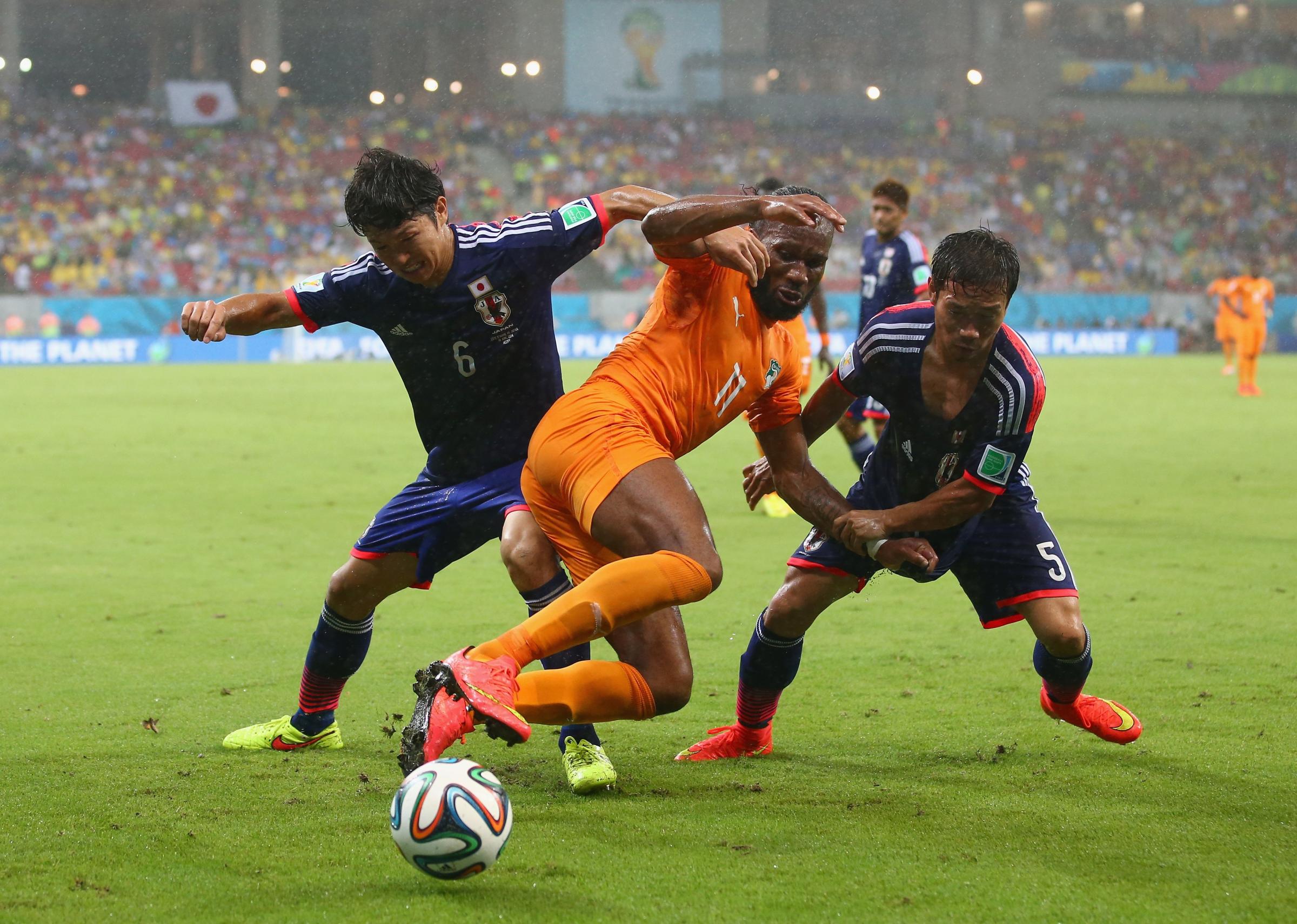 Masato Morishige and Yuto Nagatomo of Japan challenge Didier Drogba of the Ivory Coast during the 2014 FIFA World Cup Brazil Group C match between the Ivory Coast and Japan at Arena Pernambuco on June 14, 2014 in Recife, Brazil.
