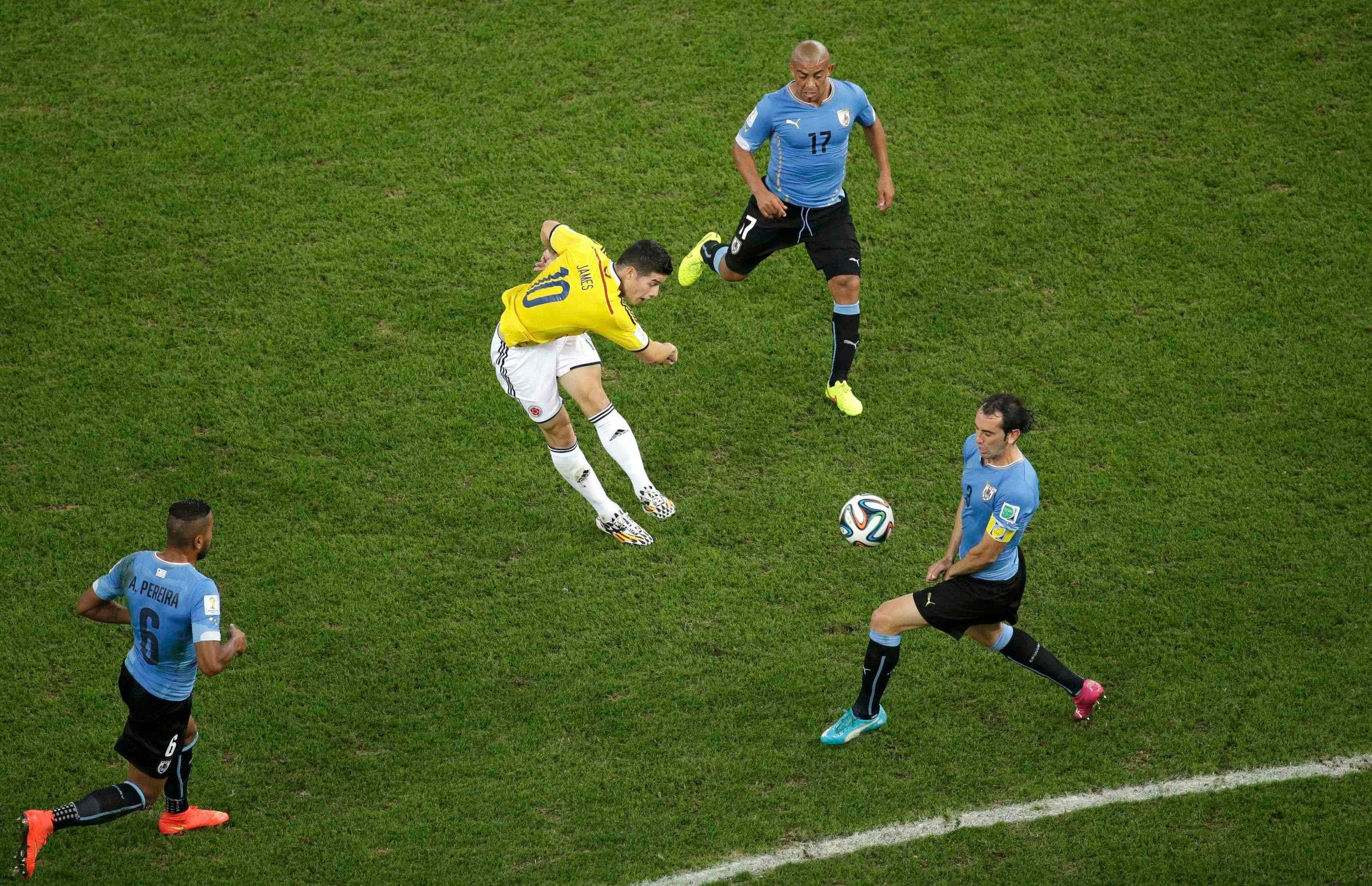 Colombia's James Rodriguez scores a goal past Uruguay's Diego Godin, Alvaro Pereira, and Egidio Arevalo Rios during their game at the Maracana stadium in Rio de Janeiro on June 28, 2014.