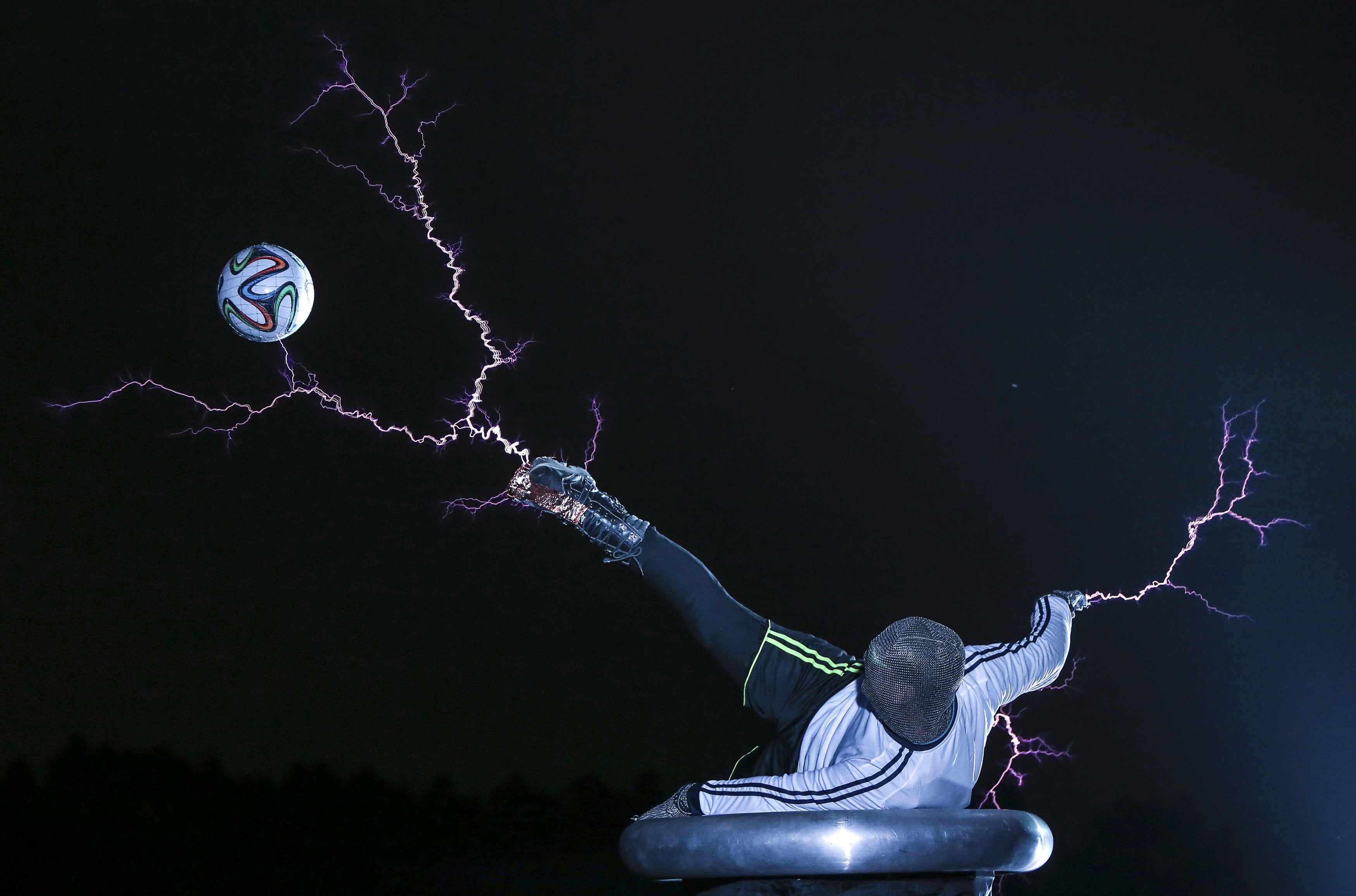 A member of the Thunderbolt Craziness band wearing a metal suit kicks a soccer ball as electricity is discharged from Tesla coils during a performance to celebrate the 2014 Brazil World Cup, in Changle, Fujian province, China on June 12, 2014.