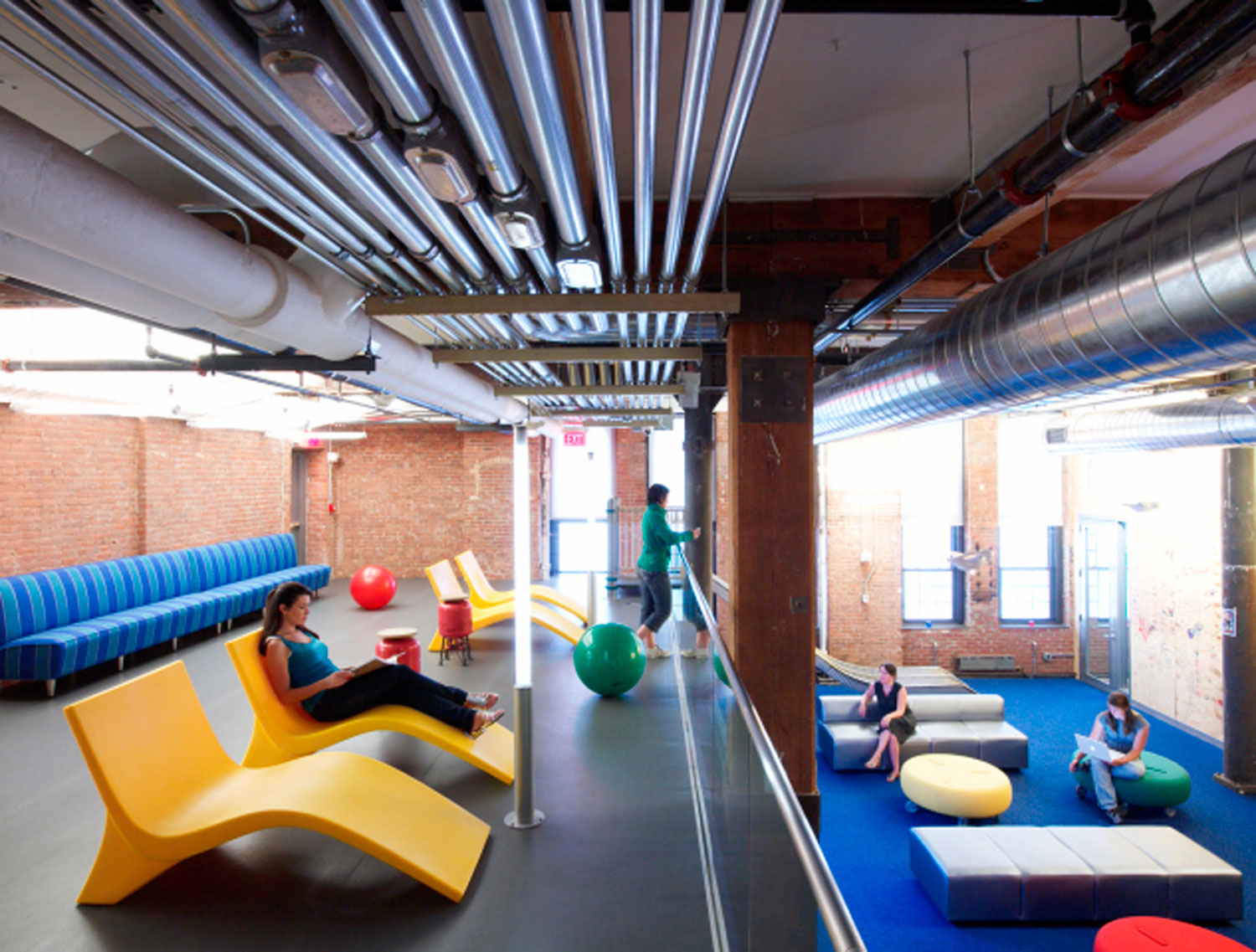 A lounge and workspace in Google's Chelsea Market office where employees can get together for a meeting or relax on a lounge chair.