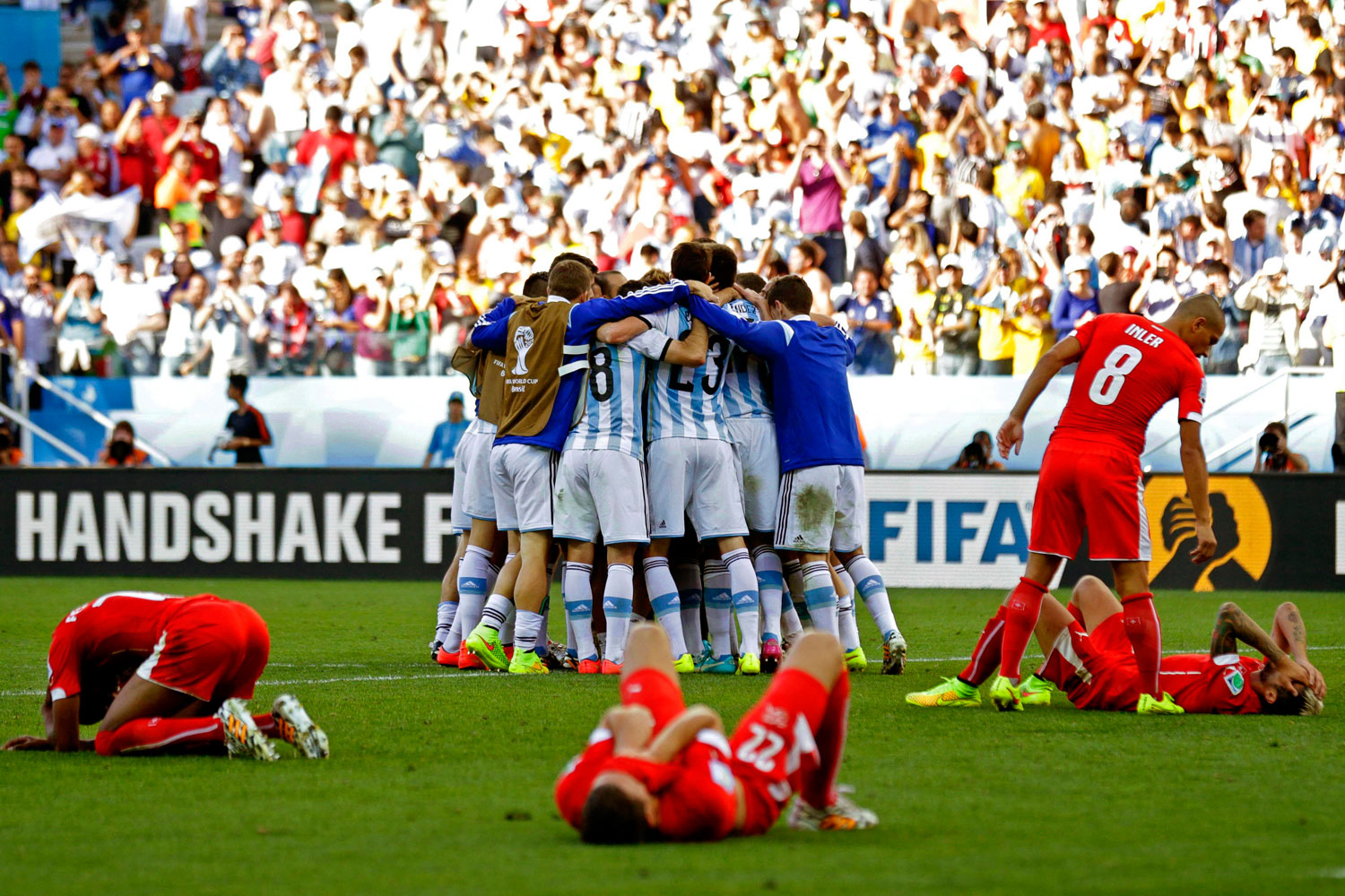 Swiss players show their dejection as Argentinian players celebrate after the FIFA World Cup 2014 round of 16 match between Argentina and Switzerland at the Arena Corinthians in Sao Paulo, Brazil on July 1, 2014.