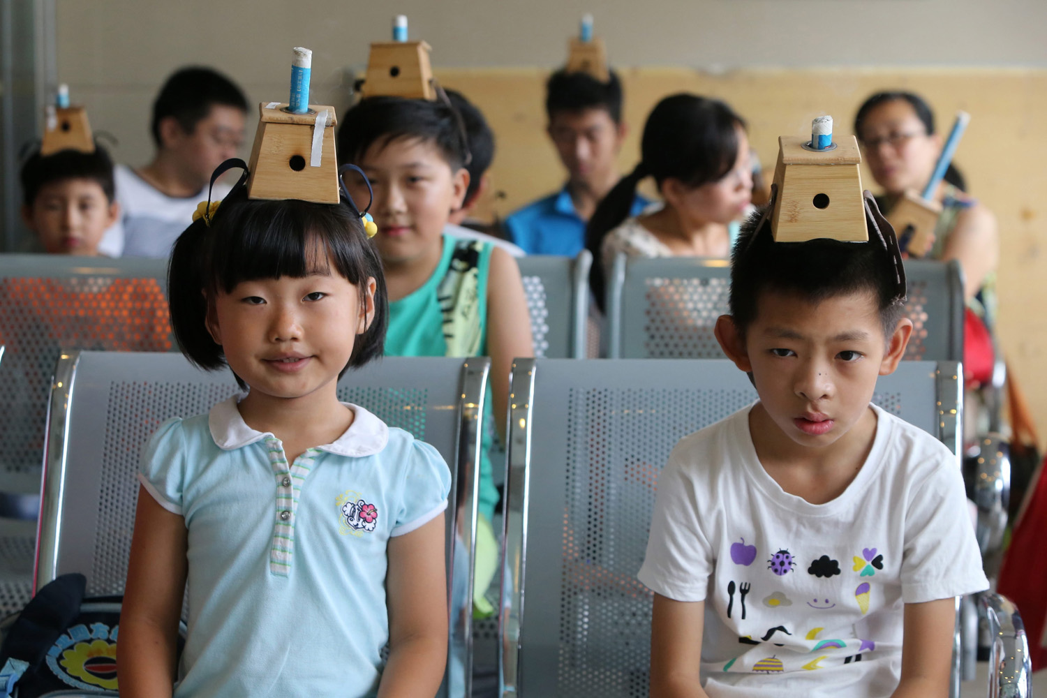 Children accept traditional Chinese medical treatment with moxibustion boxes on their heads in a hospital in Qingdao city, China on July 18, 2014.