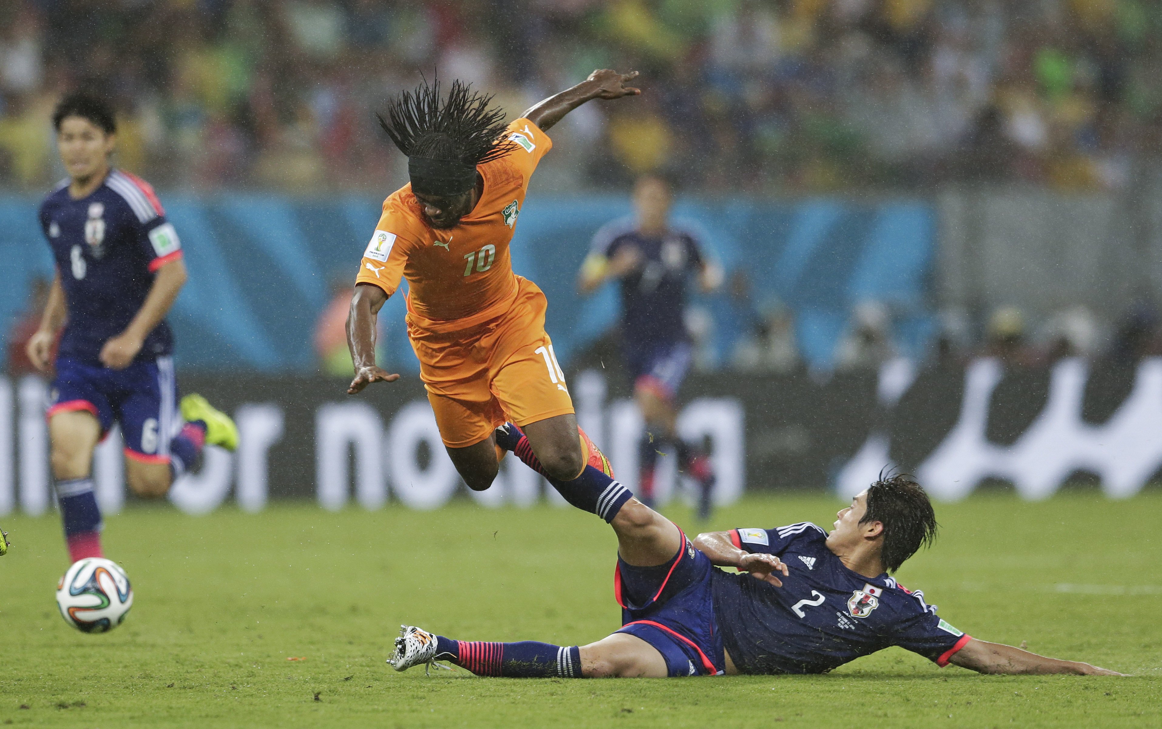 Ivory Coast's Gervinho is tripped by Japan's Atsuto Uchida during the match at the Arena Pernambuco in Recife, Brazil on June 14, 2014.