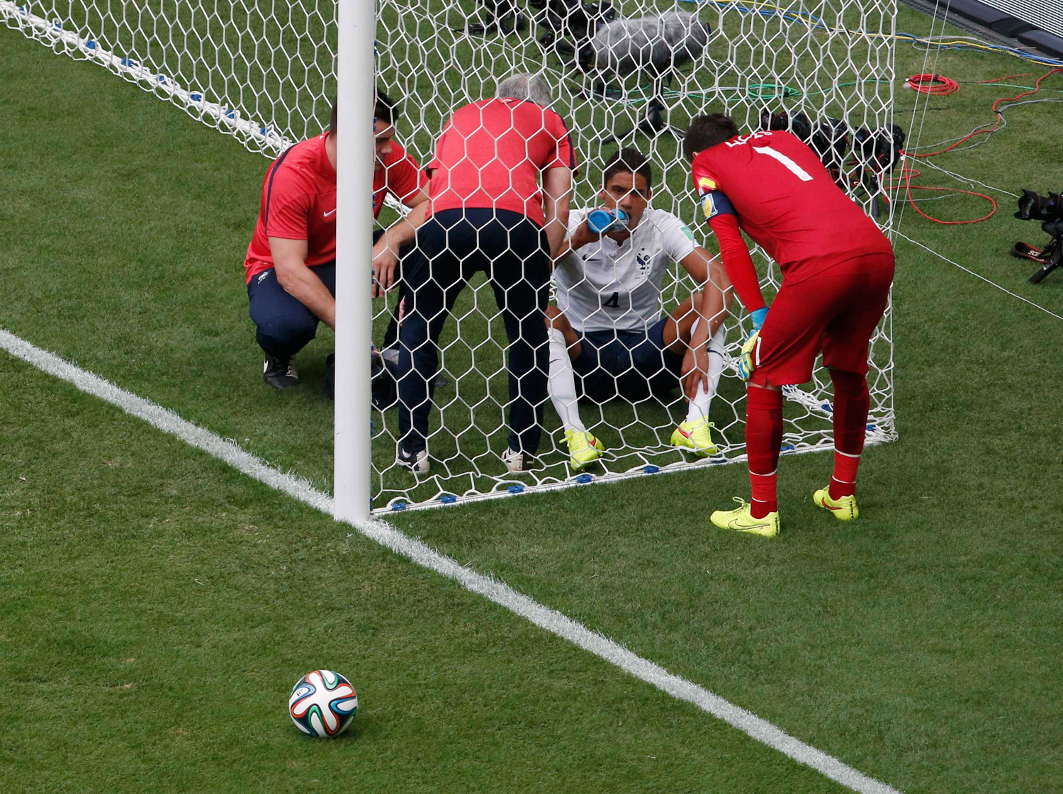 France's goalkeeper Hugo Lloris looks at teammate Raphael Varane who sits in the net after being hit in the face by a ball, during their game against Nigeria at the Brasilia National Stadium in Brasilia, Brazil on June 30, 2014.