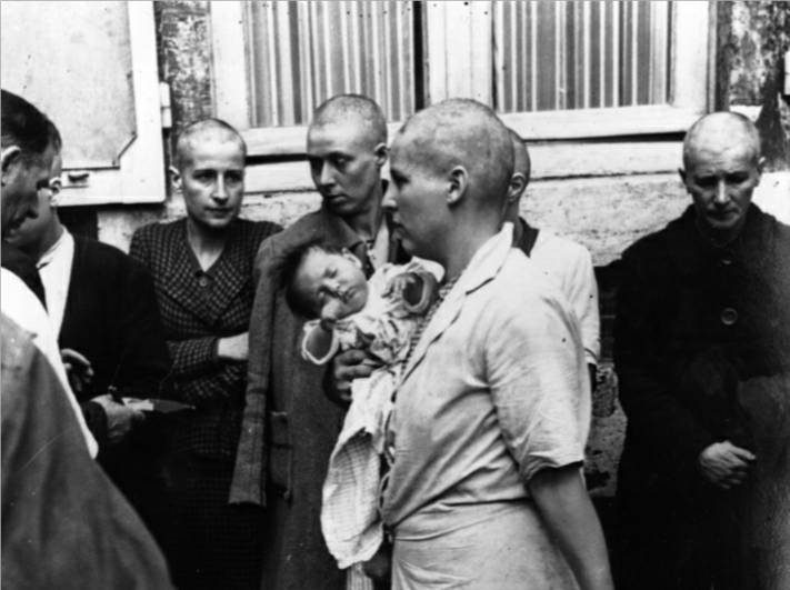 A French woman collaborator and her baby, whose father is German, returns to her home after having her head shaven following the capture of Chartres by the Allies, August 1944.