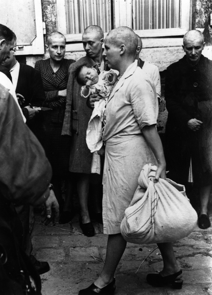 A French woman collaborator and her baby, whose father is German, returns to her home after having her head shaven following the capture of Chartres by the Allies, August 1944.