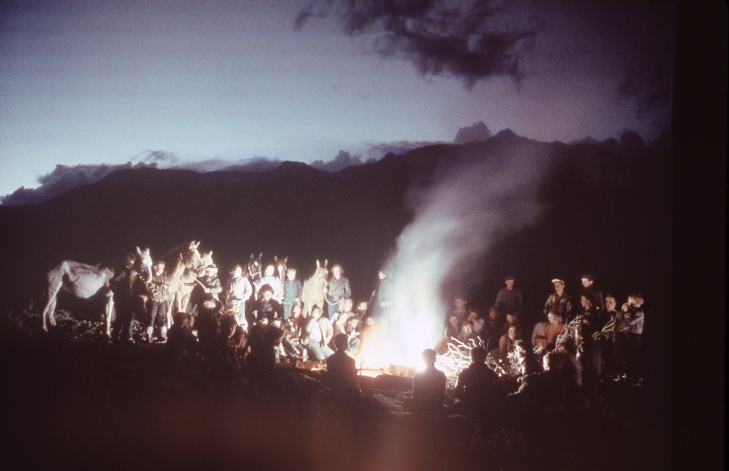 Safe in camp, boys and girls gather around a fire to sing school songs. Their geology trip has time for fishing and playing Commando among big rocks.