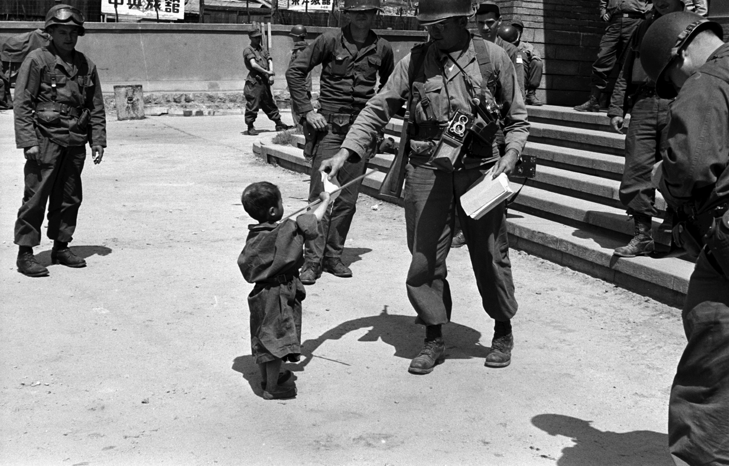 Korean War orphan Kang Koo Ri with American troops, 1951.