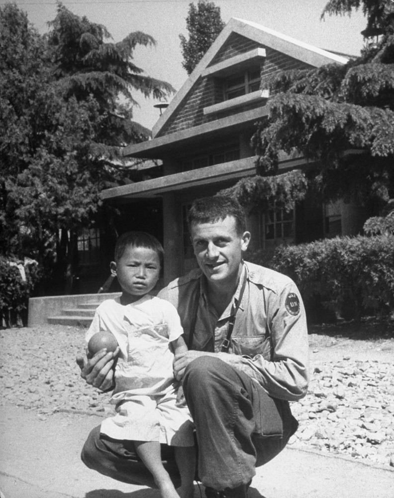 LIFE photographer Michael Rougier with war orphan Kang Koo Ri, Korea, 1951.