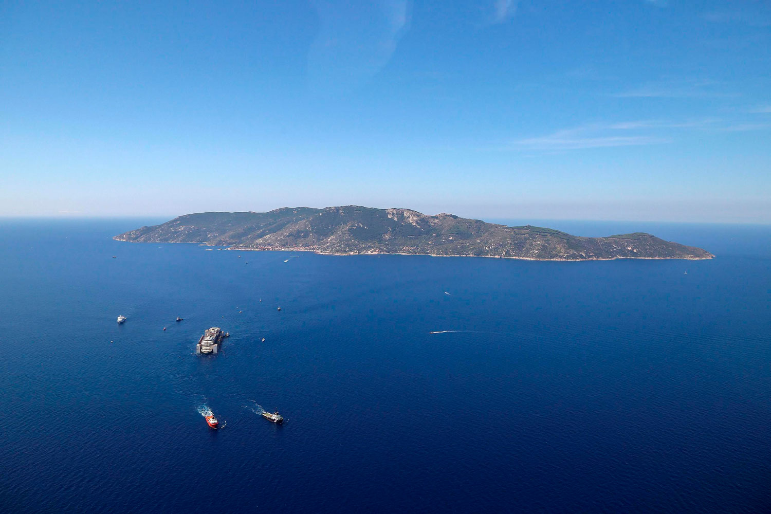 An aerial photo of the wrecked Italian cruise liner the Costa Concordia as it is towed on its final journey to the port of Genoa, Italy from Giglio Island, Italy 240 kilometers away on July 23, 2014.