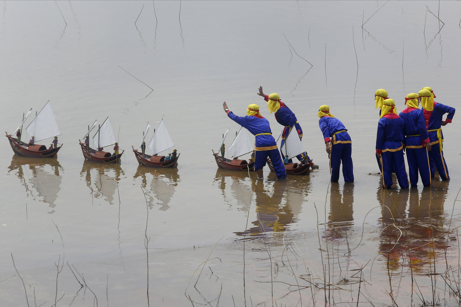 Fishermen from Ly Son island release miniature fishing boat models with artificial soldiers into water during re-enactment of Khao Le The Linh ceremony at a Vietnam Cultural village in Dong Mo