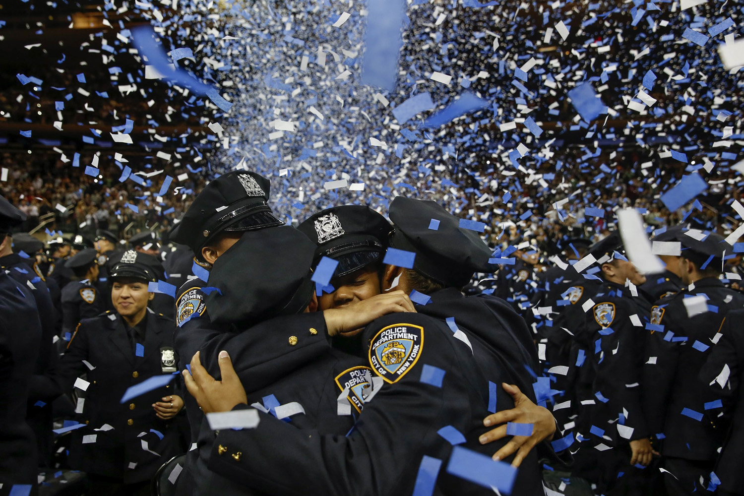 Members of the June 2014 graduating class of the New York City Police Academy embrace during their graduation ceremony at Madison Square Garden in New York