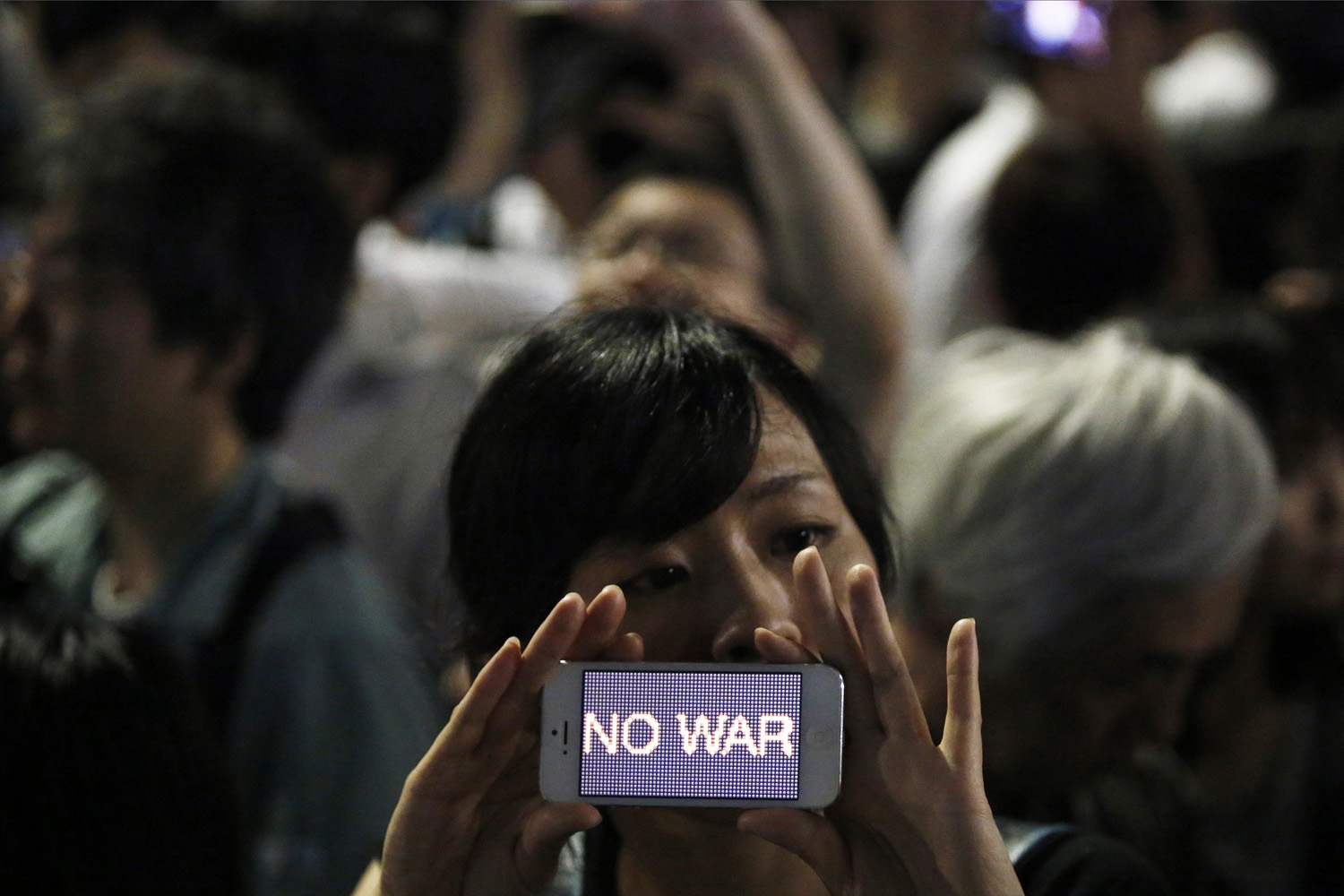 A protester holds her smartphone displaying the phrase "NO WAR" at a rally against Japan's Prime Minister Abe's push to expand Japan's military role in front of Abe's official residence in Tokyo