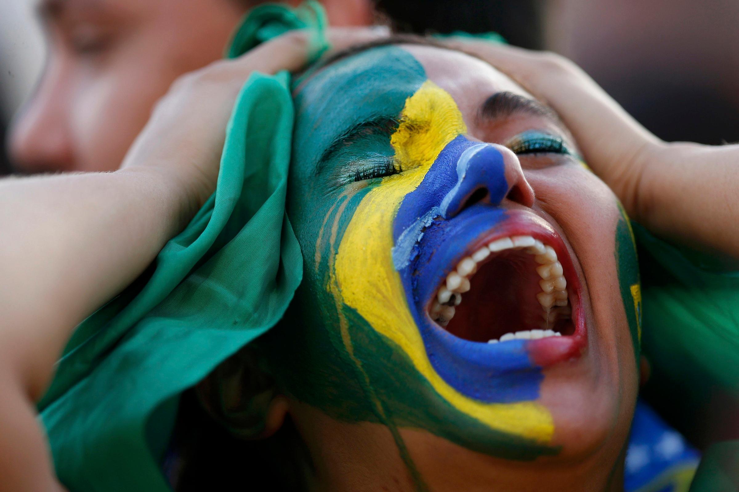Fans of Brazil react while watching a broadcast of the 2014 World Cup semi-final against Germany at the Fan Fest in Brasilia