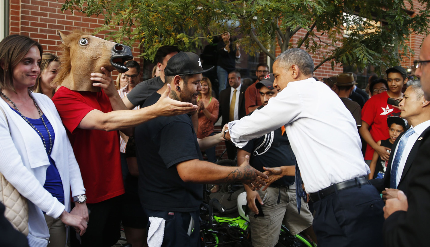 A man wearing a horse mask reaches out to shake hands with U.S. President Barack Obama during a walkabout in Denver