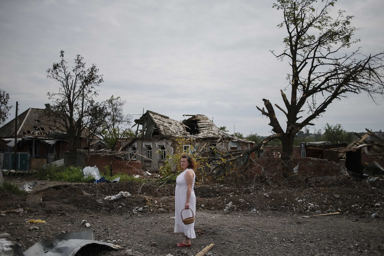 A local resident stands outside buildings damaged by a recent shelling in Semenovka