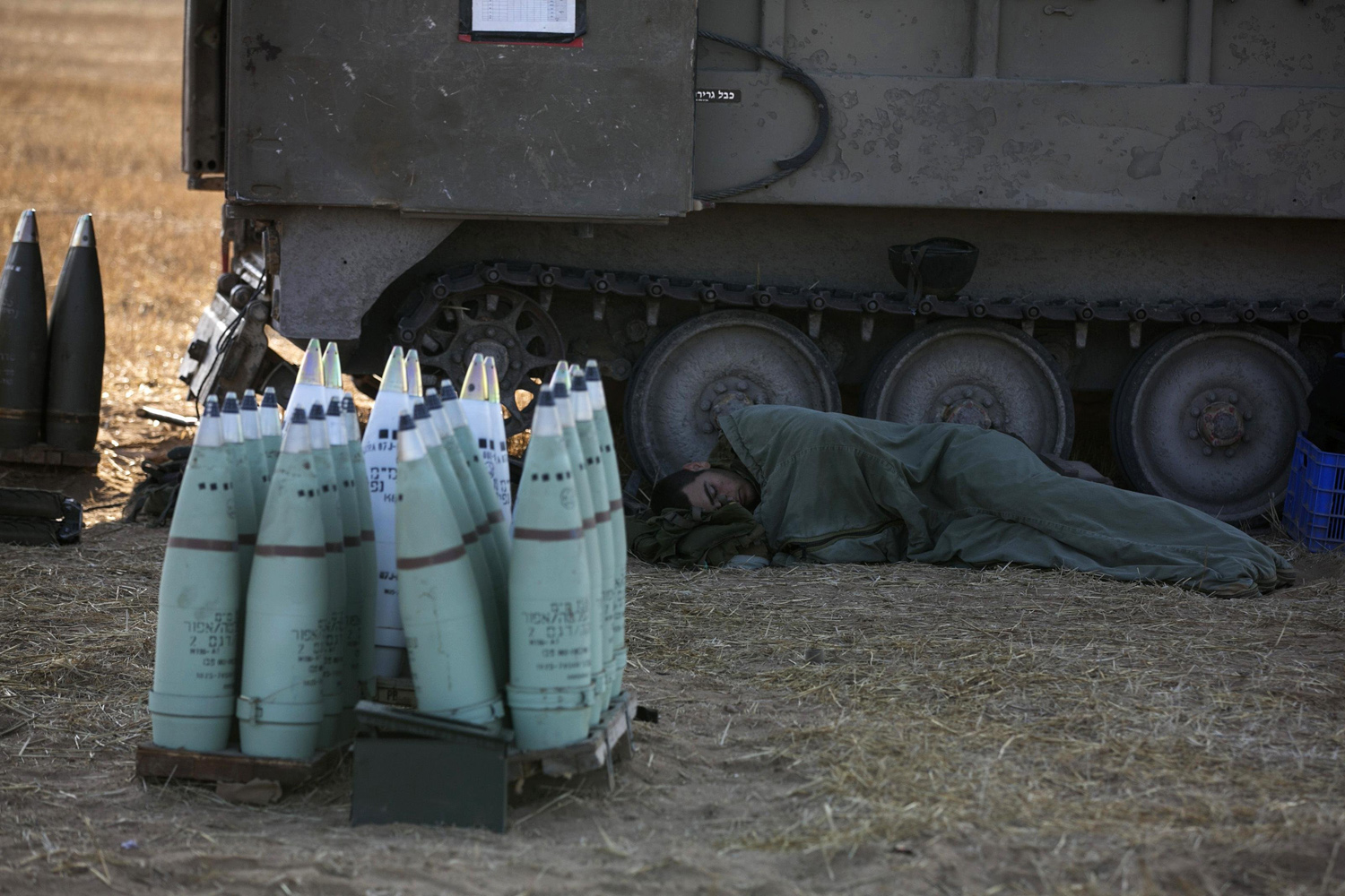 An Israeli soldier sleeps next to a mobile artillery unit outside the central Gaza Strip