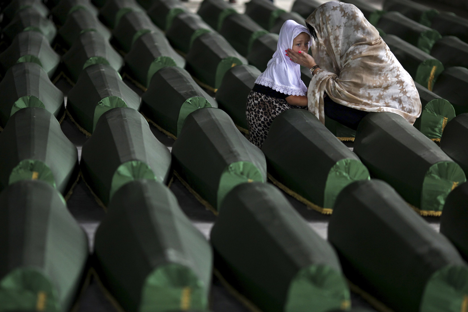 A Bosnian Muslim woman and child cry near the coffin of their relative, which is one of the 175 coffins of newly identified victims from the 1995 Srebrenica massacre, in the Potocari Memorial Center, near Srebrenica