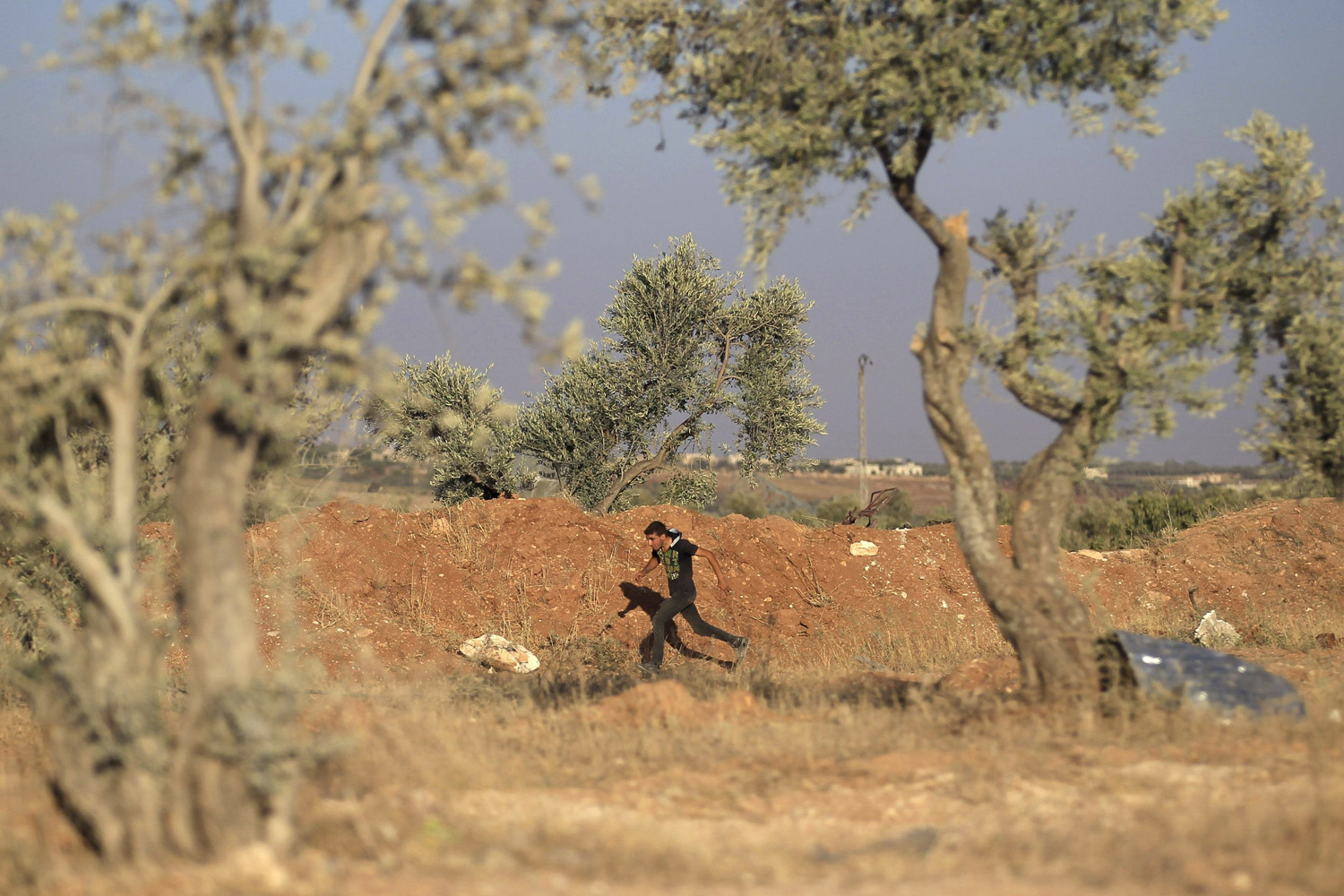A Free Syrian Army fighter runs to avoid snipers loyal to Syria's President Bashar al-Assad in the southern Idlib countryside
