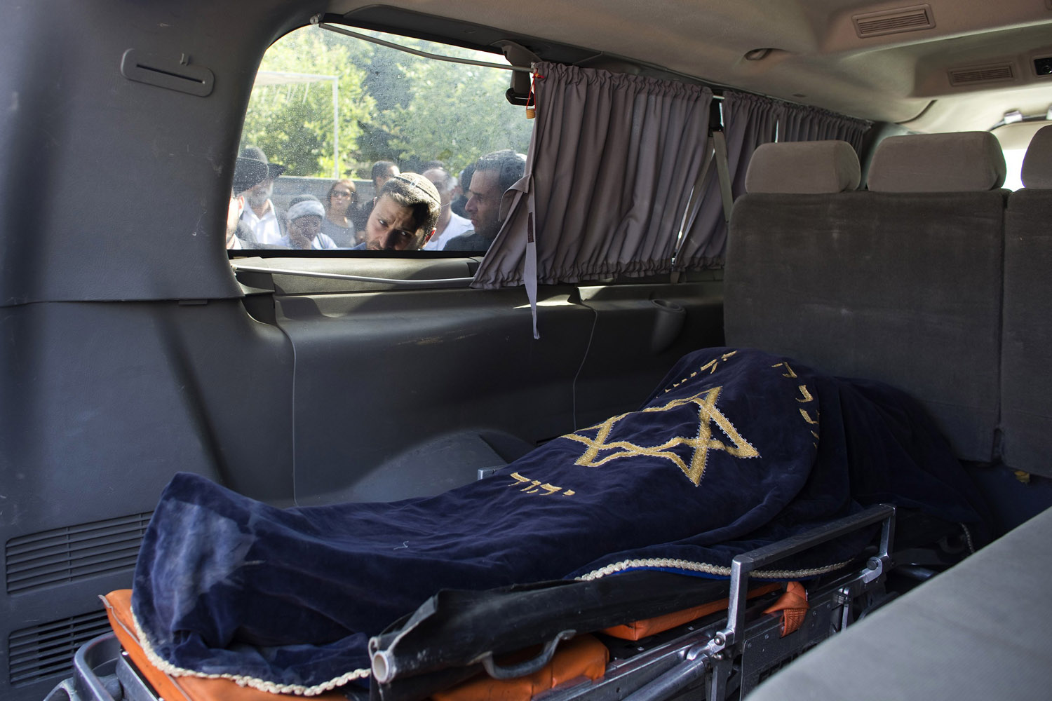 An Israeli looks through the window of a van carrying the body of Dror Khenin before his funeral in Yehud, after Khenin was killed on Tuesday by a rocket