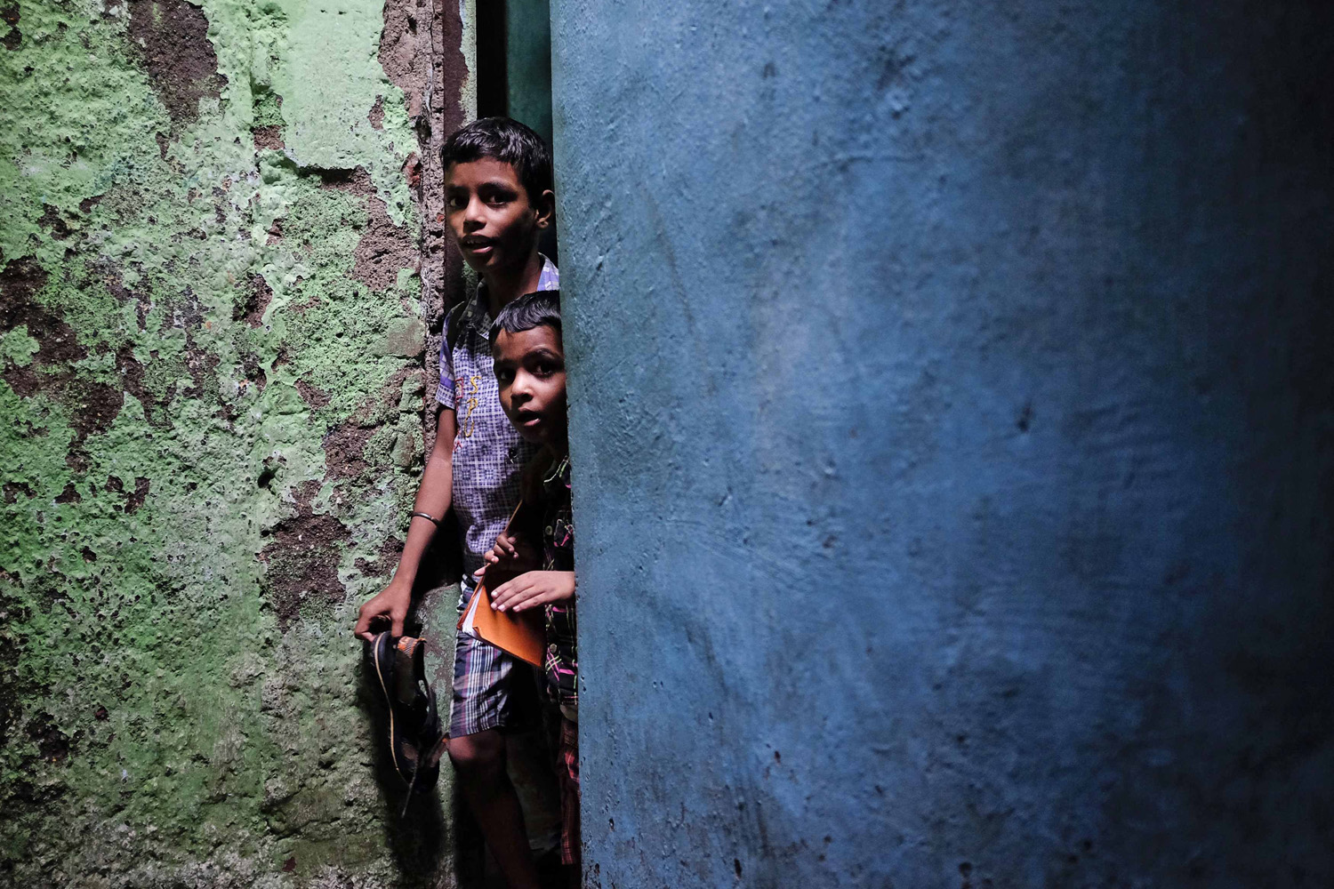 Schoolchildren walk through an alley after attending private tuition at a slum in Mumbai