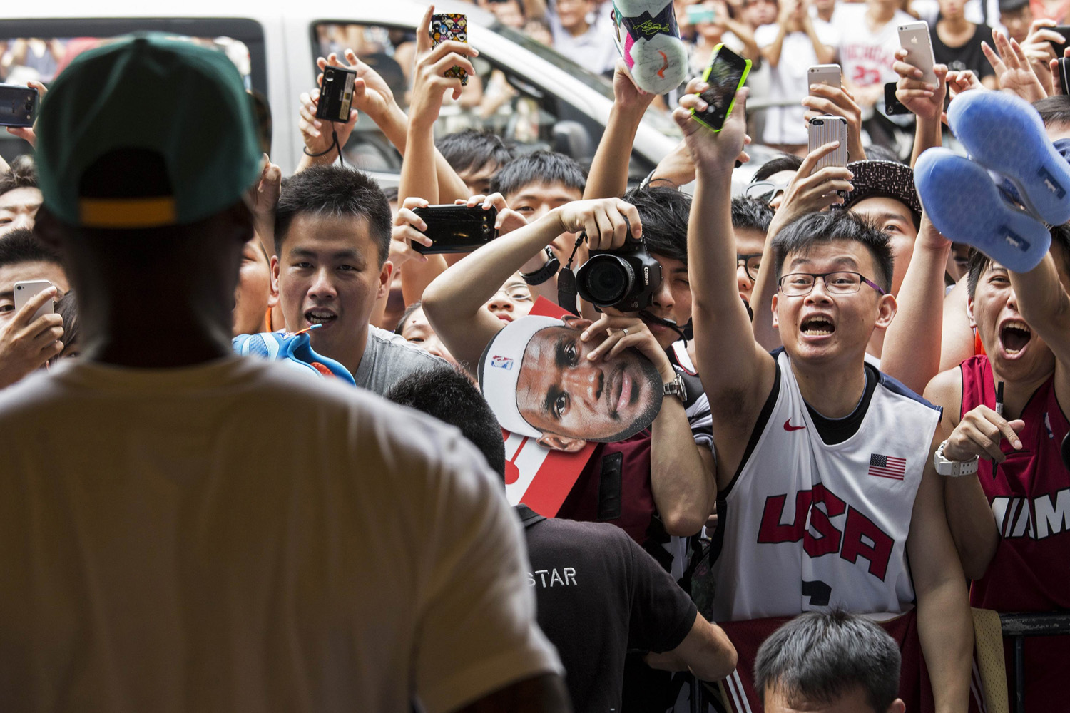 Fans wave and yell at NBA basketball player LeBron James (L) of the Cleveland Cavaliers during a promotional event in Hong Kong on July 23, 2014.