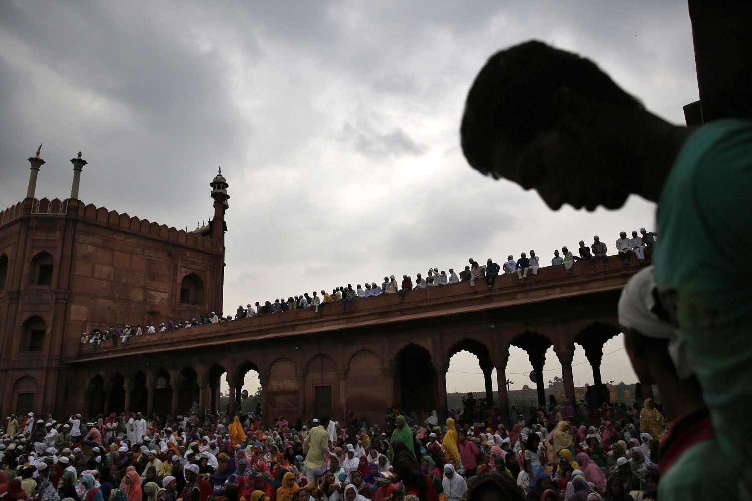 Muslims sit inside the compound of Jama Masjid (Grand Mosque) before the start of last Friday prayers of the holy fasting month of Ramadan in the old quarters of Delhi