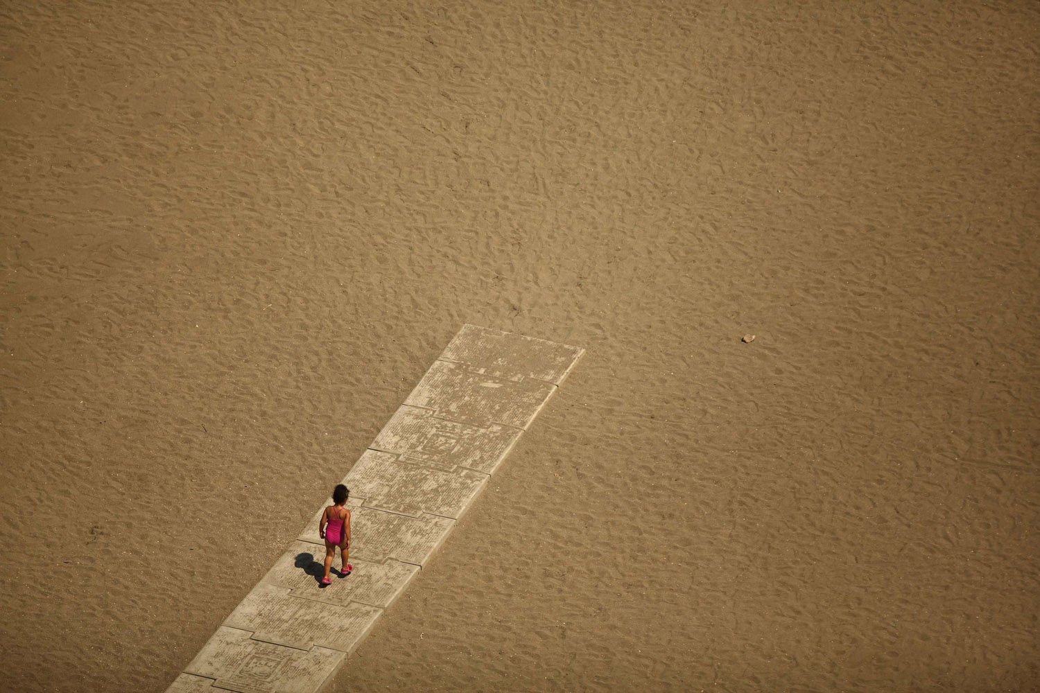 Child walks toward the shore of the Malagueta beach at the Mediterranean Sea in Malaga