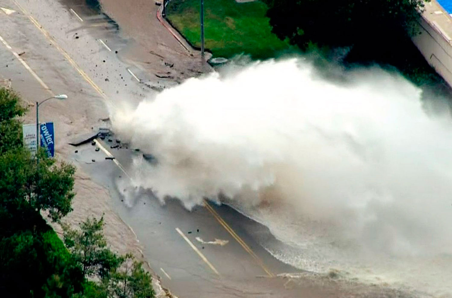 Water gushes from a broken water main on Sunset Boulevard on the UCLA campus in Los Angeles
