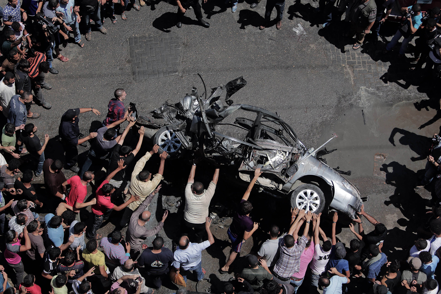 Jul. 8, 2014. Palestinians inspect a destroyed car of militants following an Israeli airstrike in central Gaza City. Israel launched a major military offensive against the Gaza Strip Tuesday in response to increasing rocket attacks by Palestinian militants.