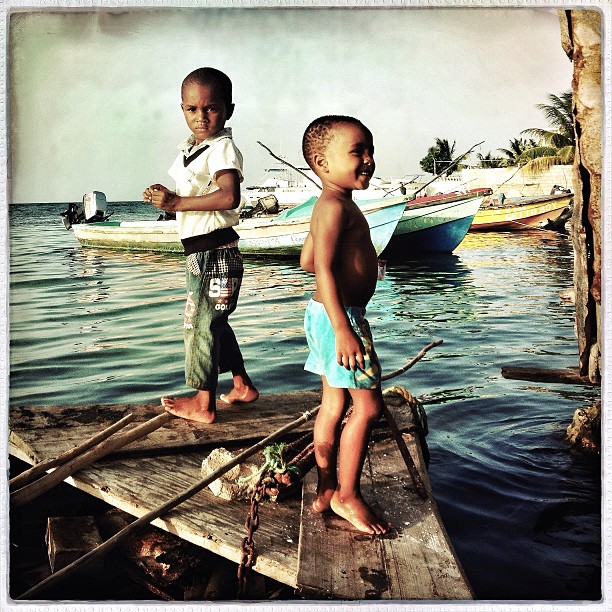 Aug 7, 2013.  Four-year-old Ryan and his friend are here throwing their line to the school of parrot fish that shoot like pinball under the bottom of their cork and bamboo boat. This, to me, is one of the most important pictures I have shot on this whole trip. He reminds me so much of a young Ruddy--barefooted, in his high water pants, and fearless.