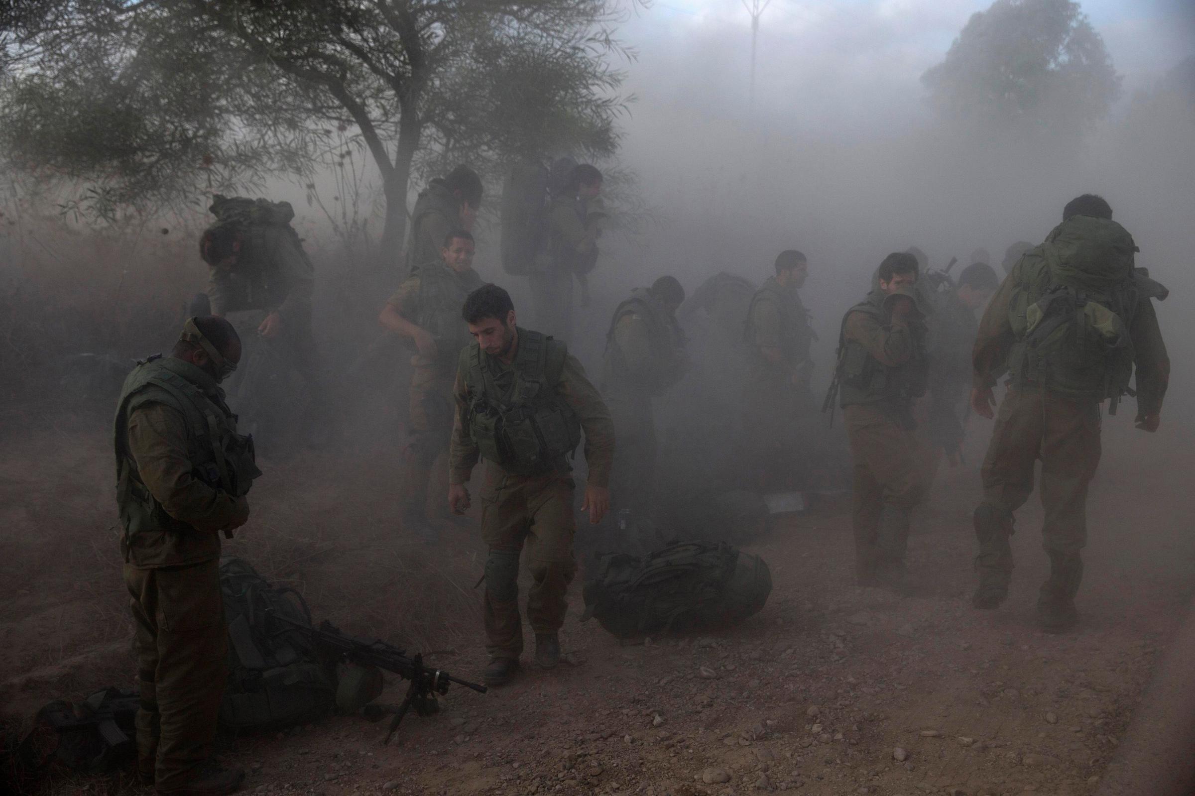 Israeli soldiers put on their gear on the side of a road across from the Gaza Strip on July 18, 2014.