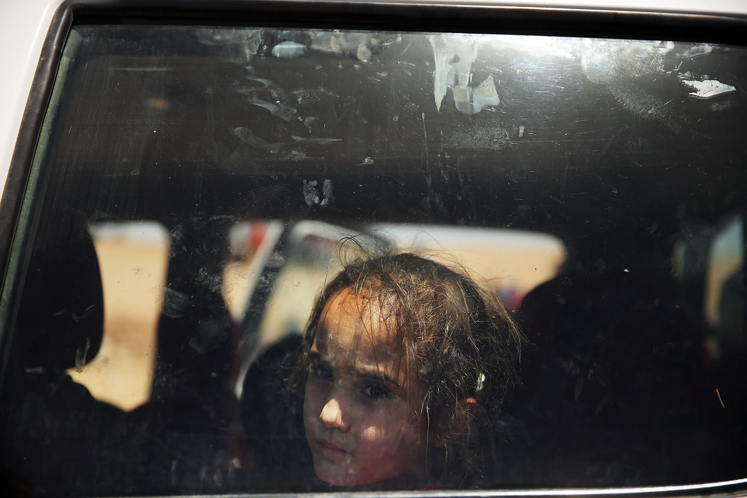 Jul. 1, 2014. An Iraqi girl look out of a window as over 1000 Iraqis who have fled fighting in and around the city of Mosul and Tal Afar wait at a Kurdish checkpoint in the hopes of entering a temporary displacement camp in Khazair, Iraq.