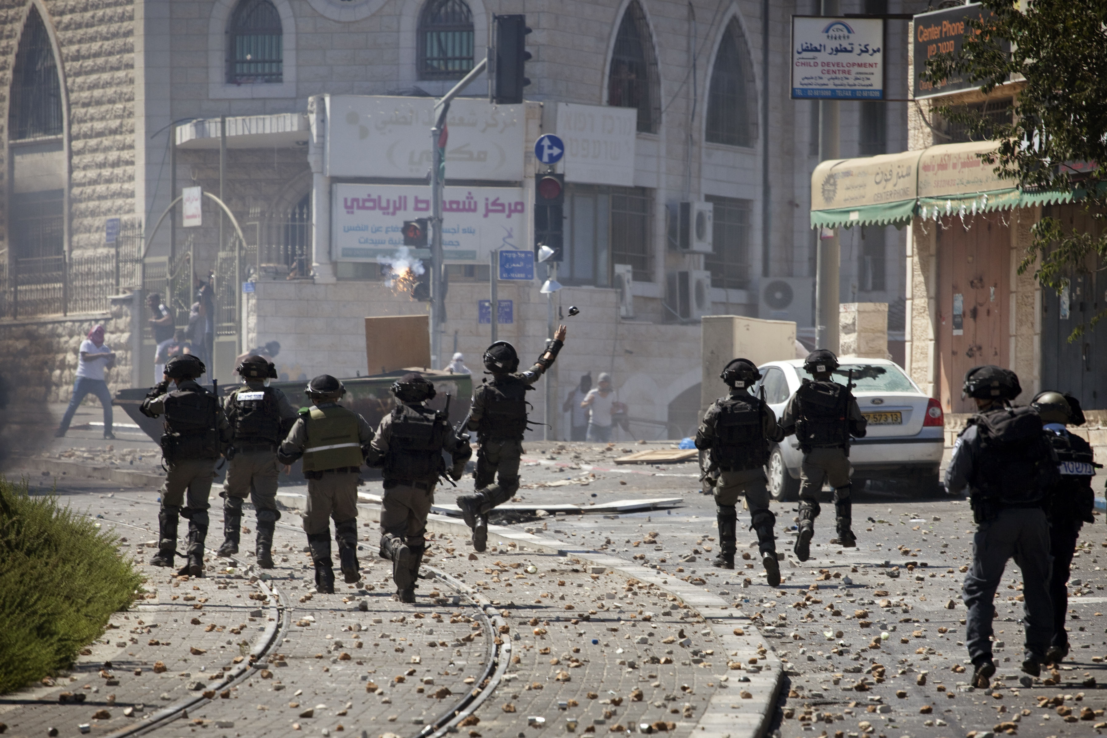 An Israeli soldier throws a grenade during clashes with
