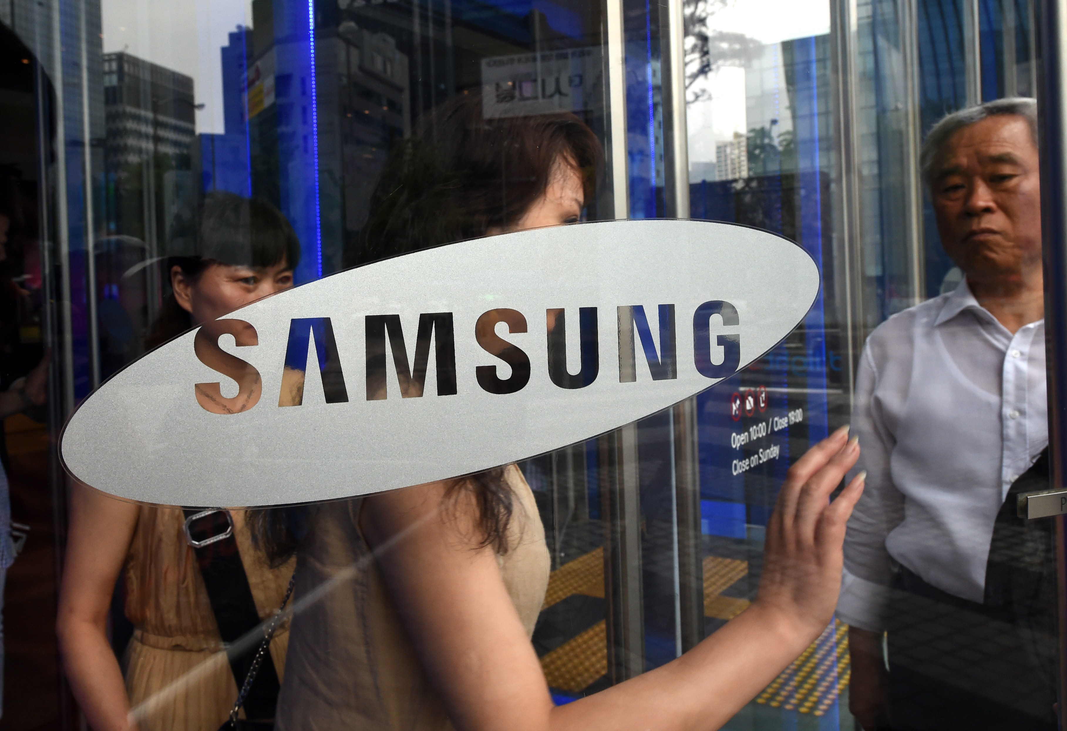 Visitors walk past a glass door showing the logo of Samsung Electronics at the company's showroom in Seoul on July 8, 2014. (Jung Yeon-Je—AFP/Getty Images)