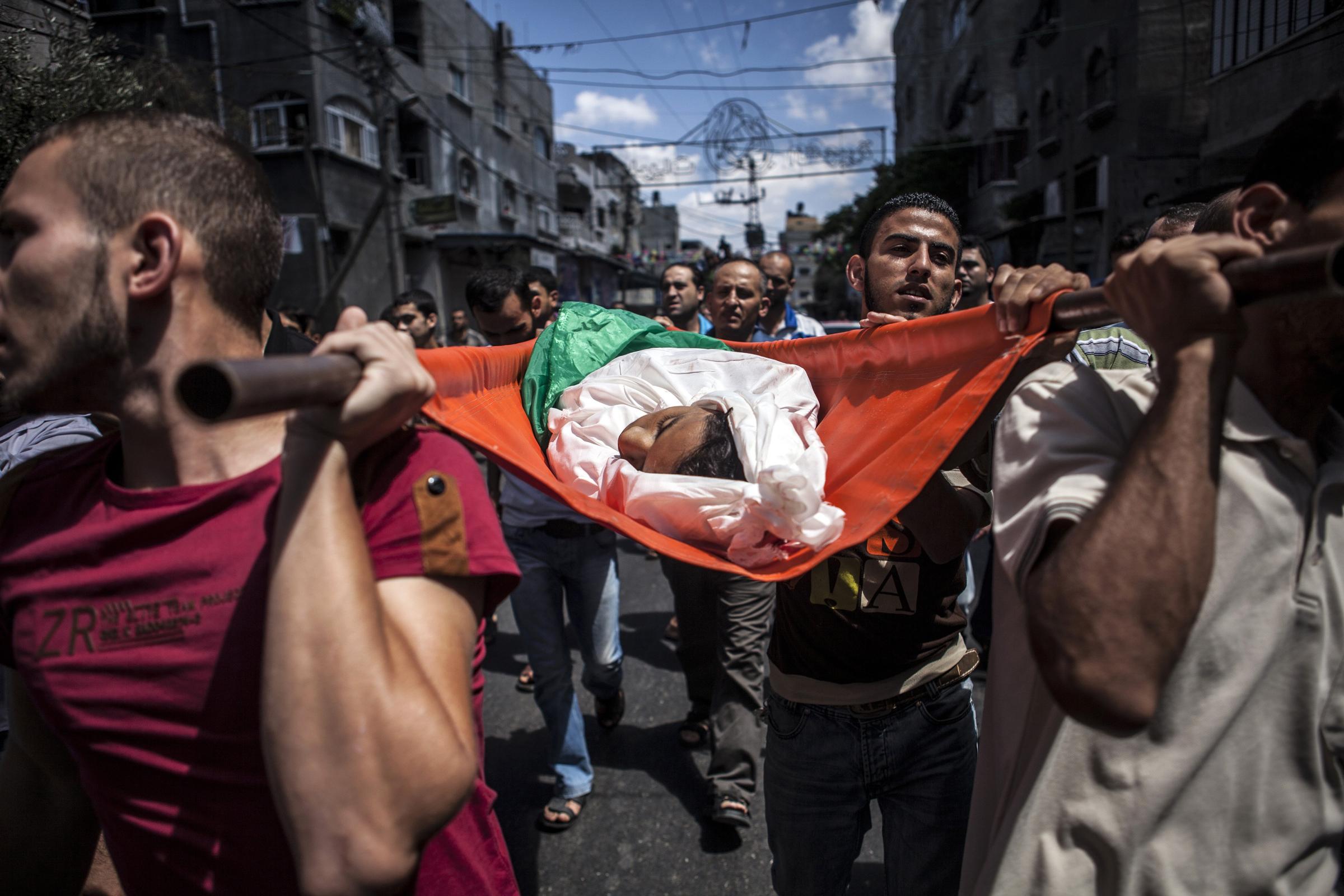 Palestinian mourners gather around the bodies of three siblings of the Abu Musallam family, during their funeral in Beit Lahiya, Gaza Strip on July 18, 2014.