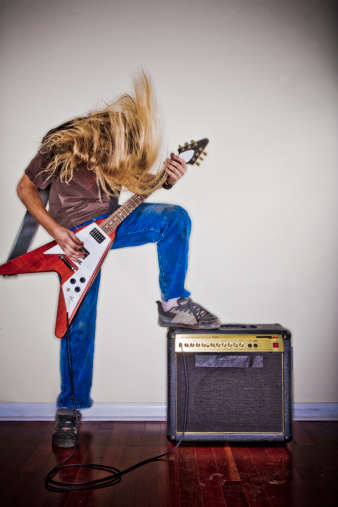 Man thrashes head while playing guitar. (Jim Arbogast—Getty Images)